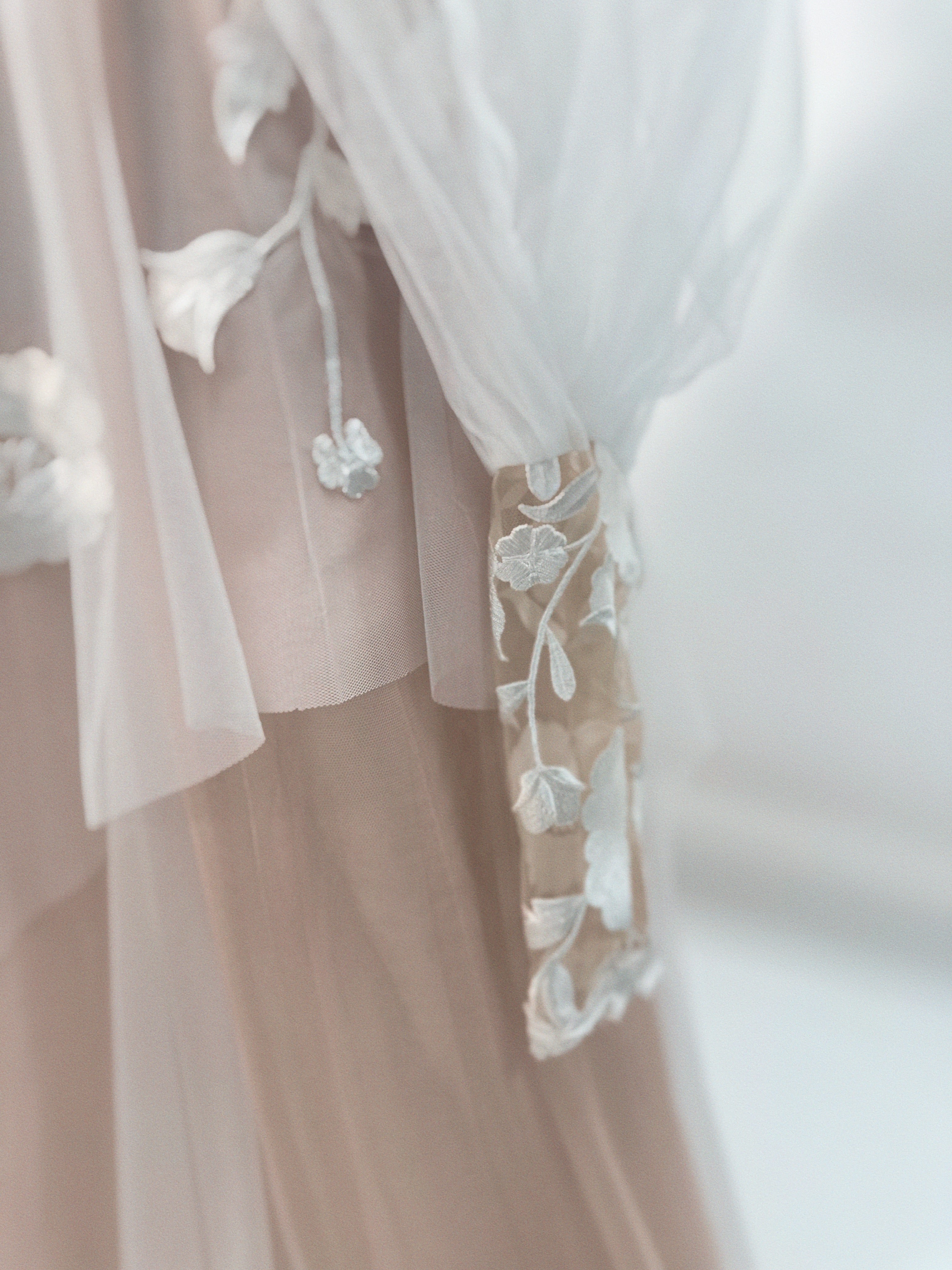 Detail of Arrowyn ethereal wedding dress featuring detachable gigot sleeve with botanical floral appliqué and illusion net.