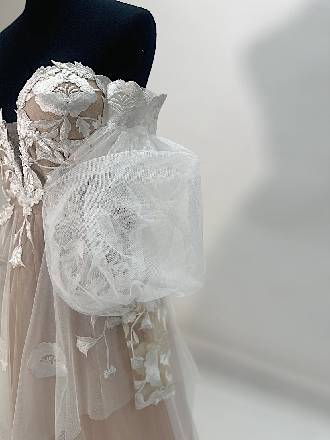 Arrowyn illusion corset wedding dress with hand-applied botanical appliqué and detachable tulle gigot sleeve.