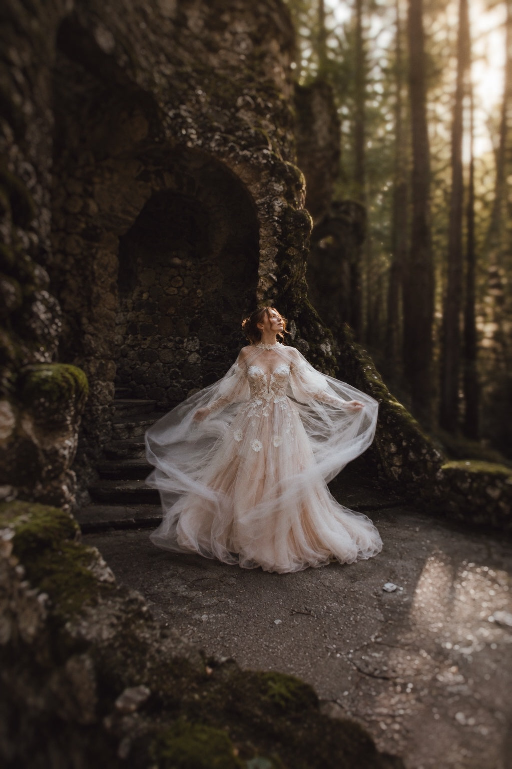 Arrowyn ethereal wedding dress with sheer floral cape and botanical appliqué in enchanted woodland setting.