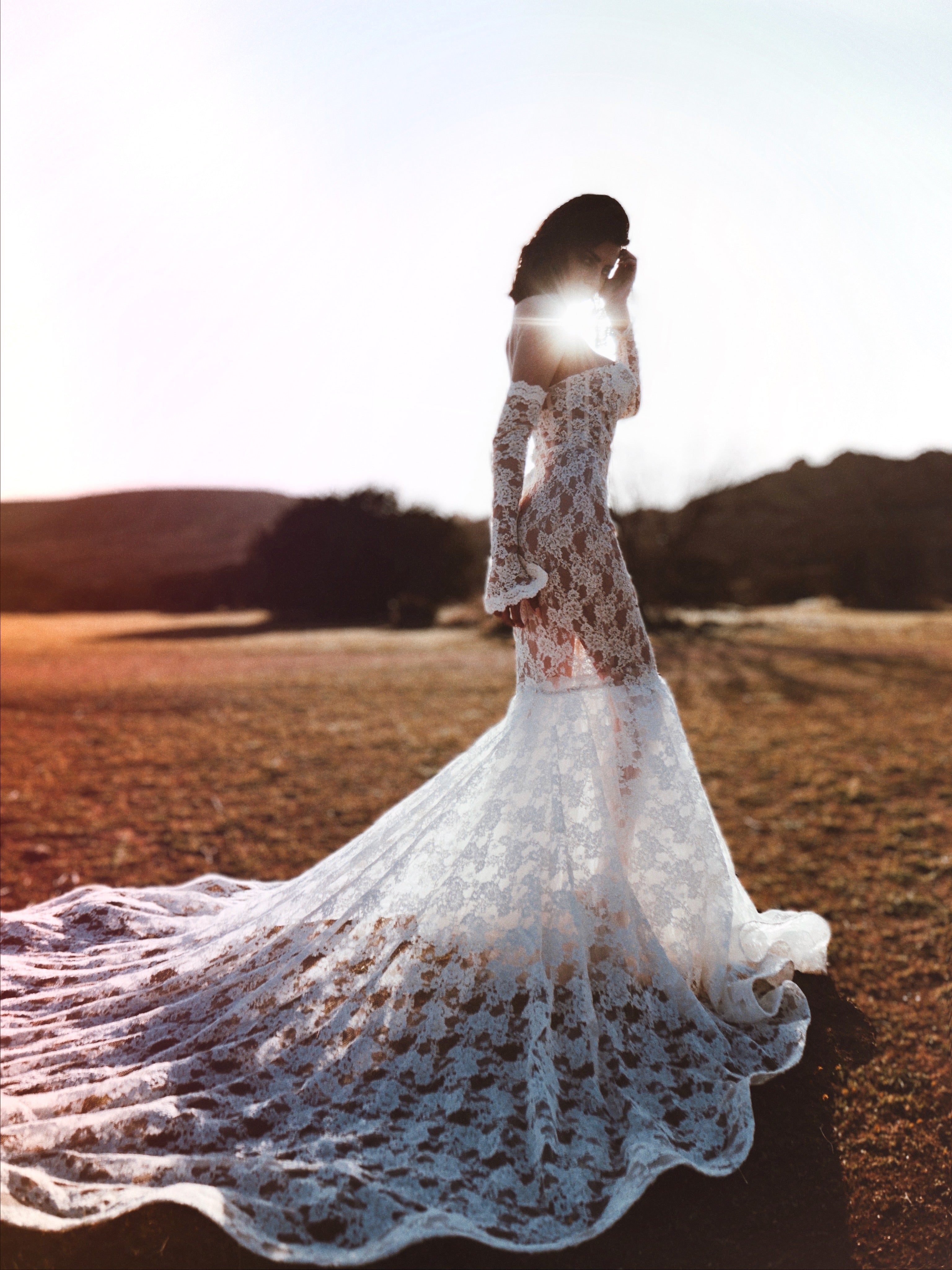 Full-length lace bridal gown with detachable lace sleeves flowing in field