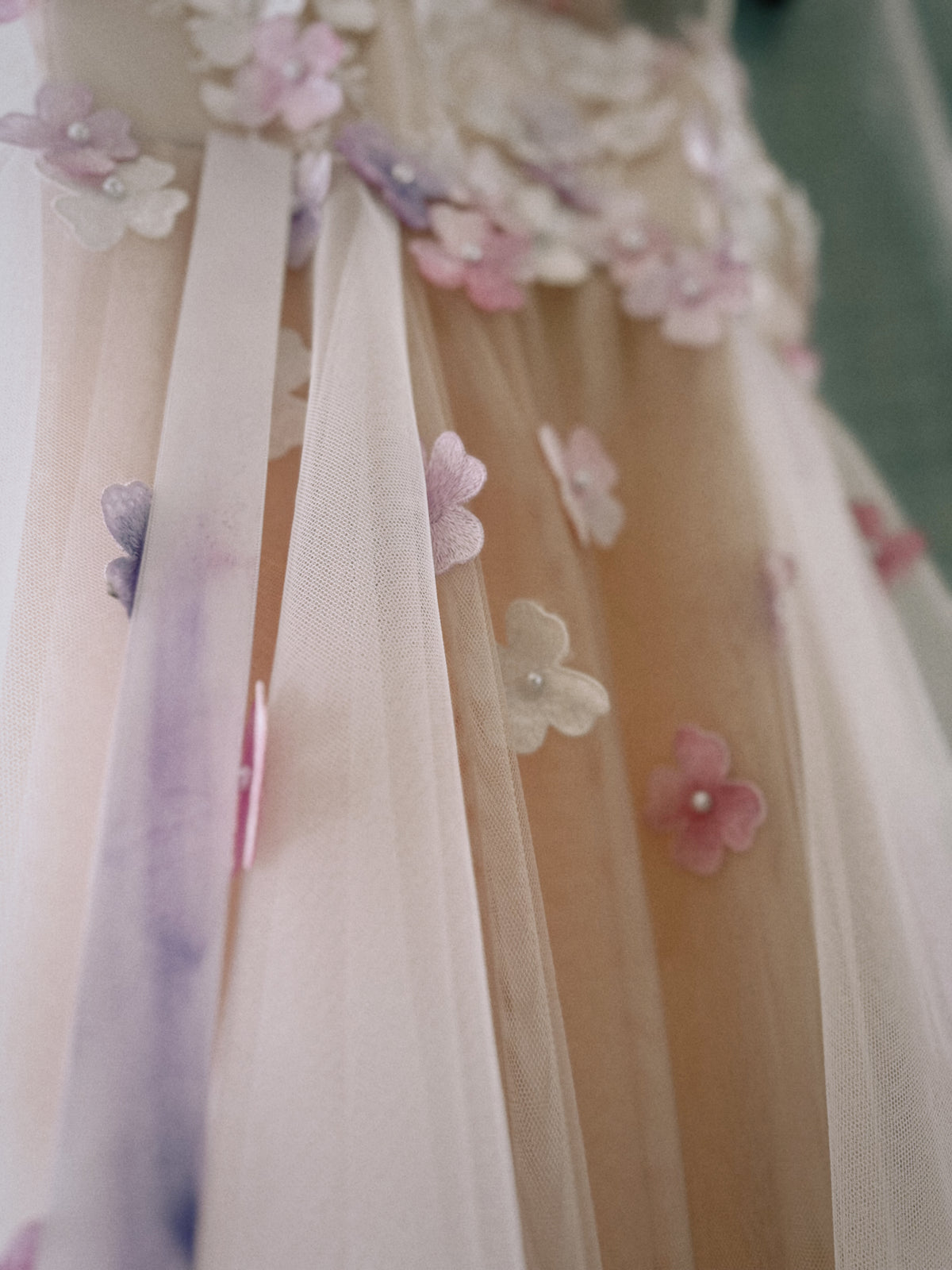 Close-up of Florêve hand-painted 3D wildflower appliqués in pink, lavender and white on sheer tulle