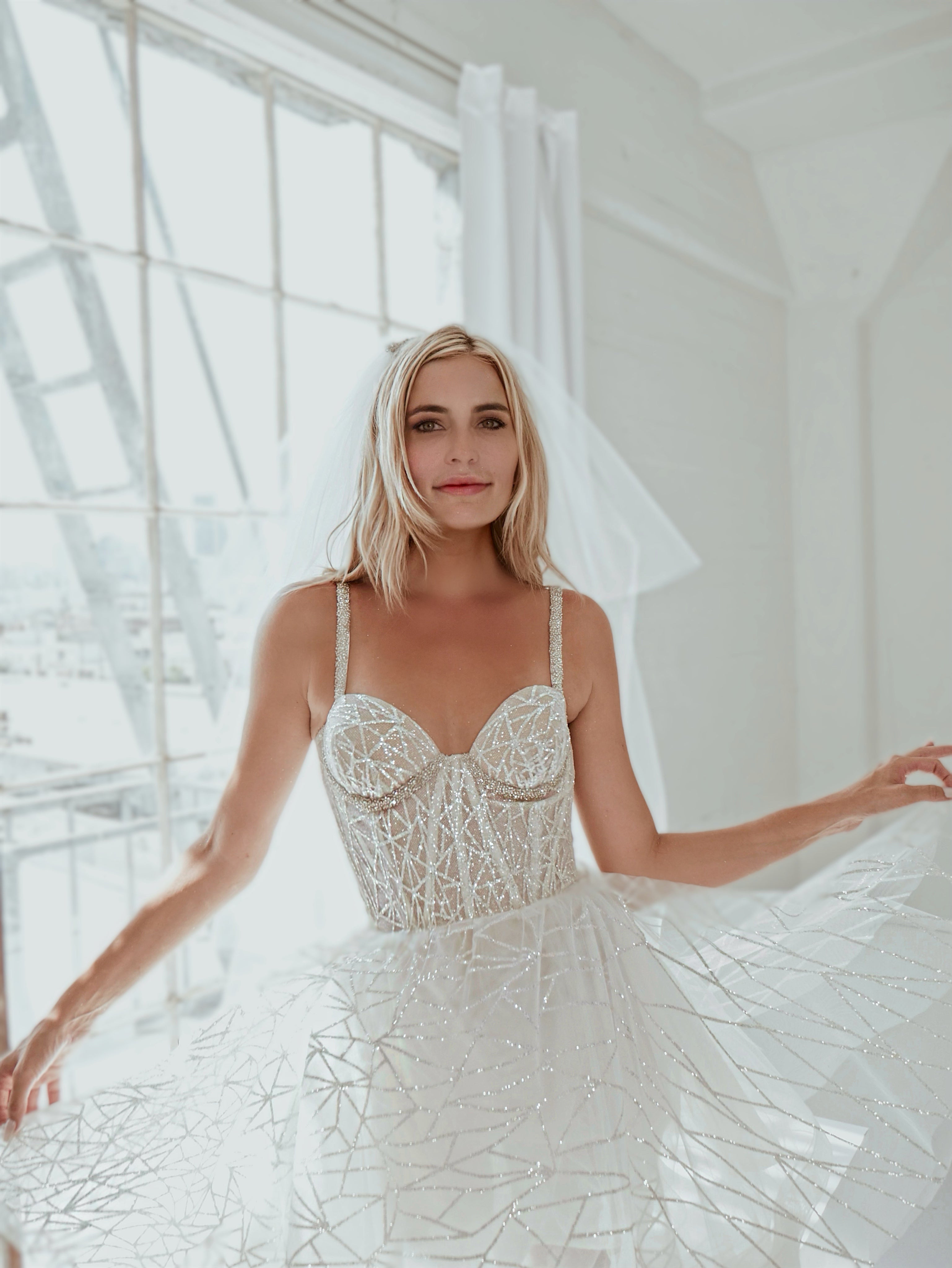 Front view of a model wearing a glamorous tiered tulle wedding veil with crystal comb.
