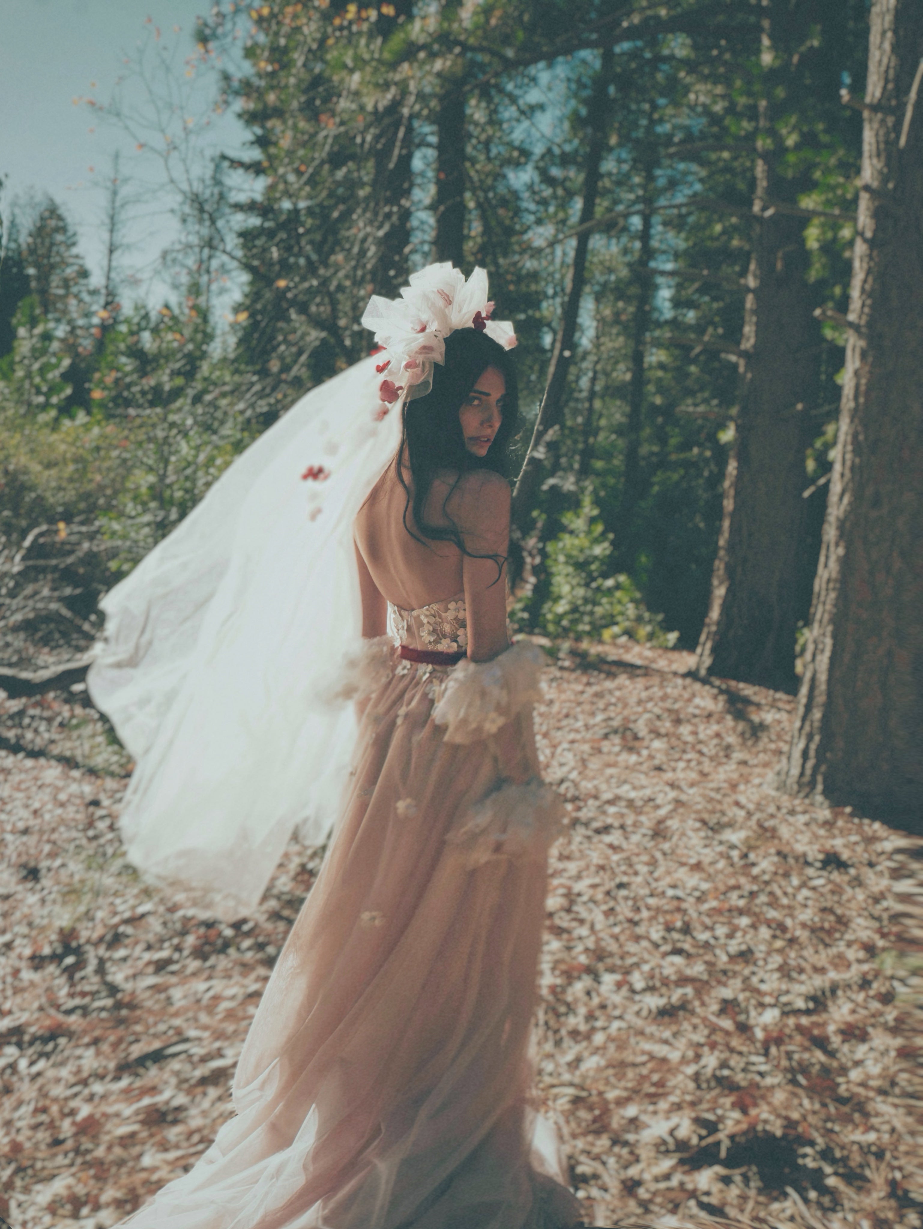 Back view of Valen bohemian wedding dress with 3D floral lace, flowing blush tulle skirt, and floral bridal veil.