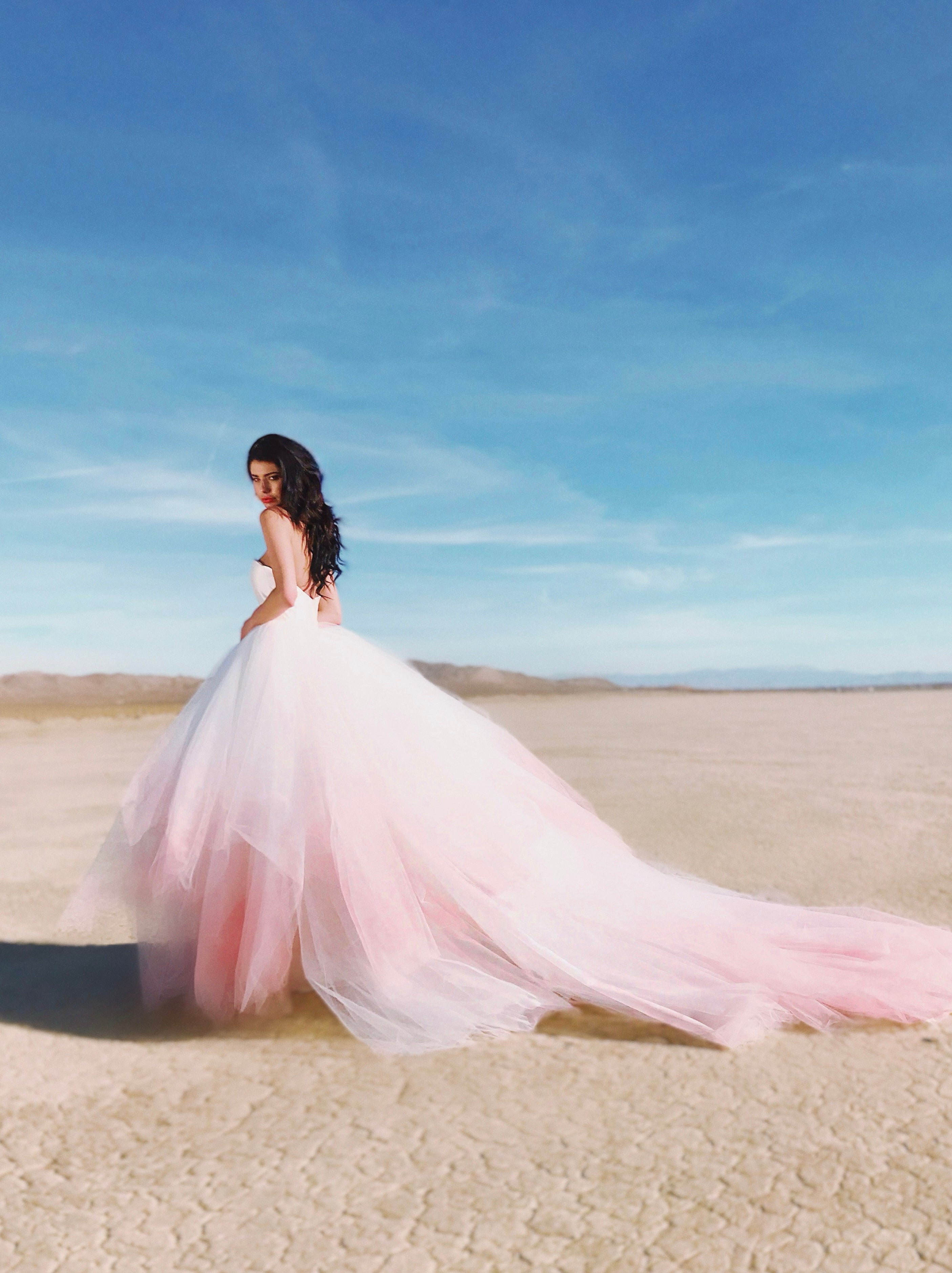Wide shot of blush ombre wedding dress with long train trailing behind