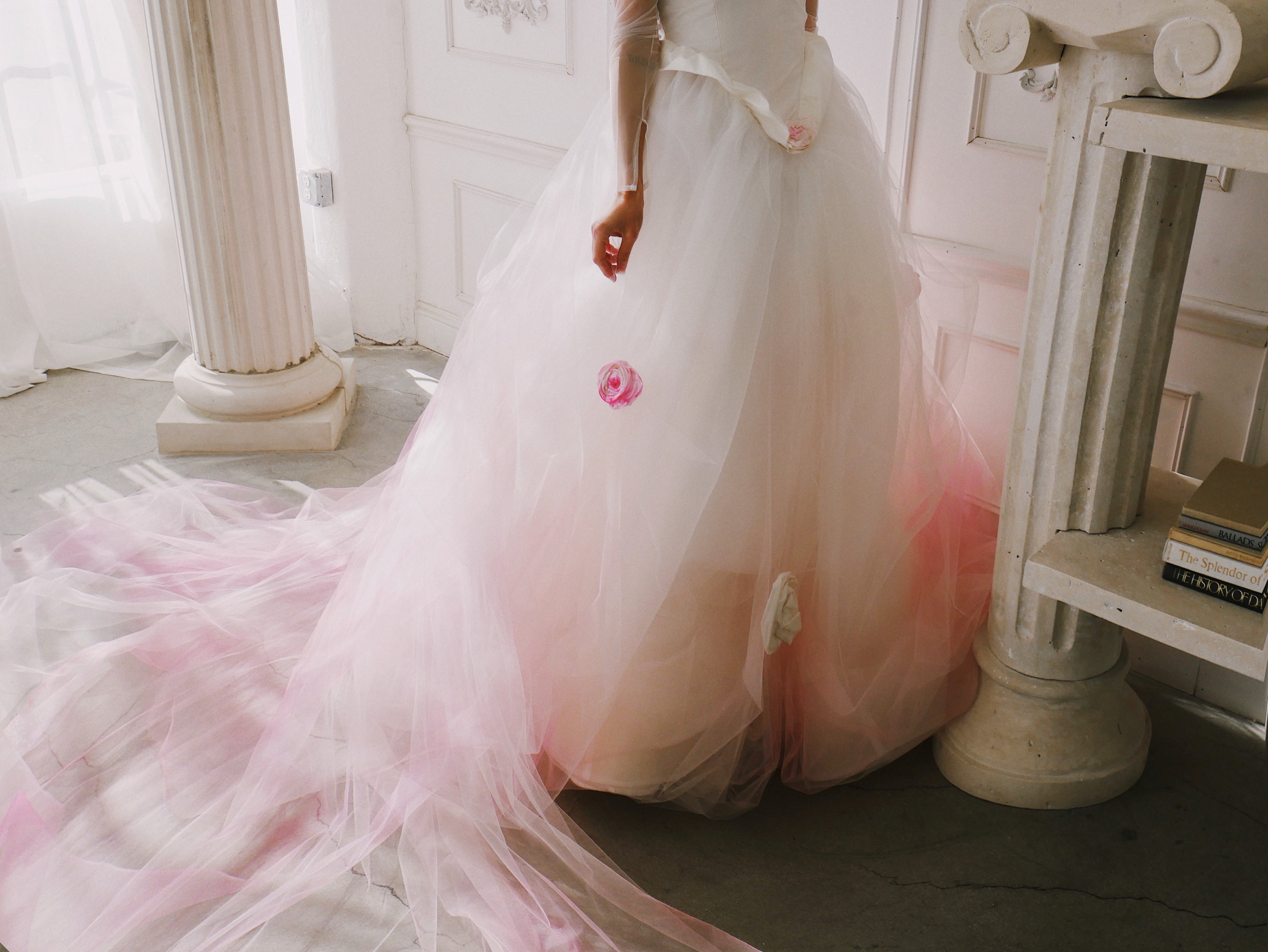 Closeup of ball gown skirt of wedding dress with blush ombre and hand painted roses