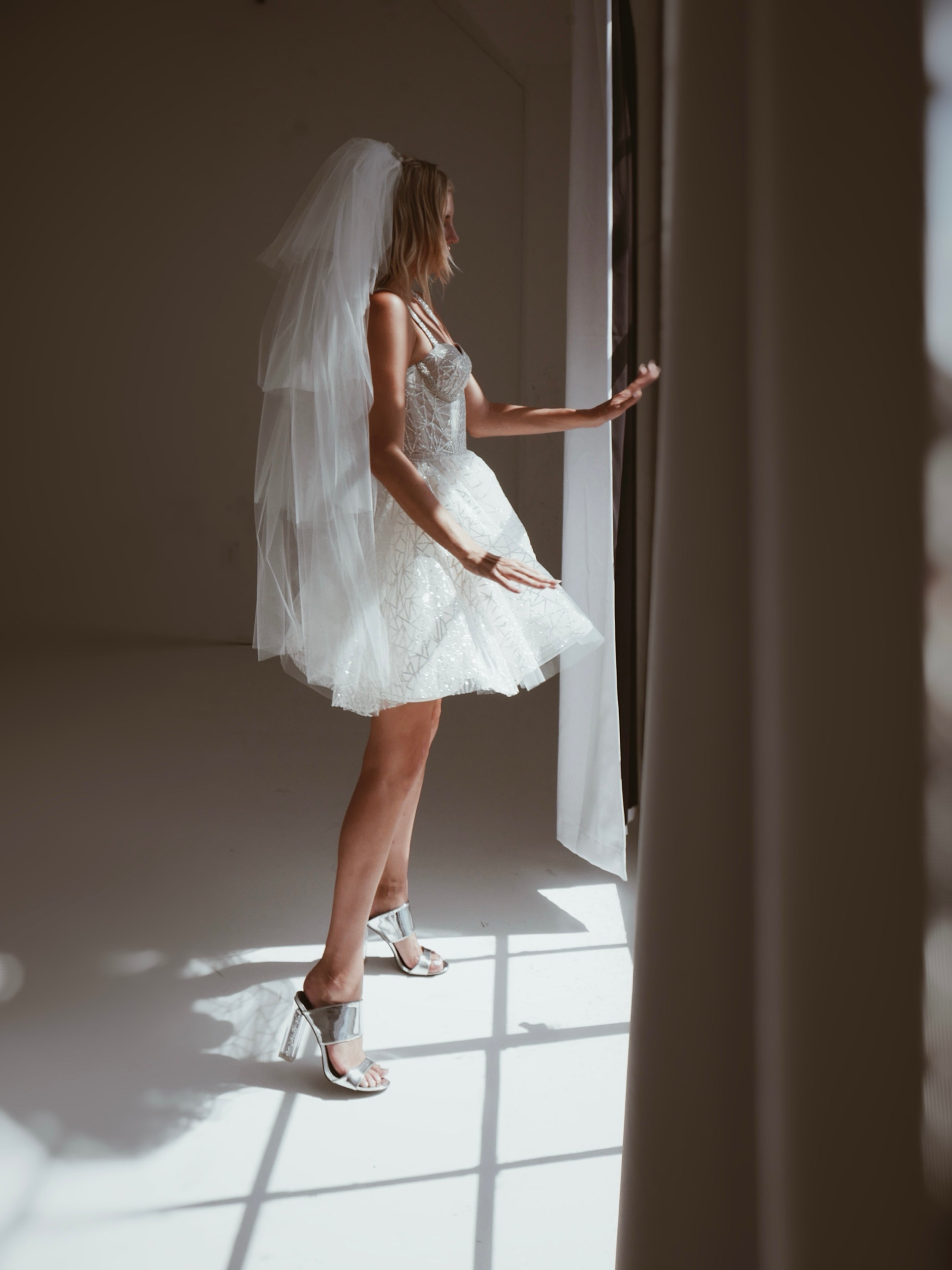 Side view of a model wearing a dramatic tiered tulle wedding veil with crystal comb.