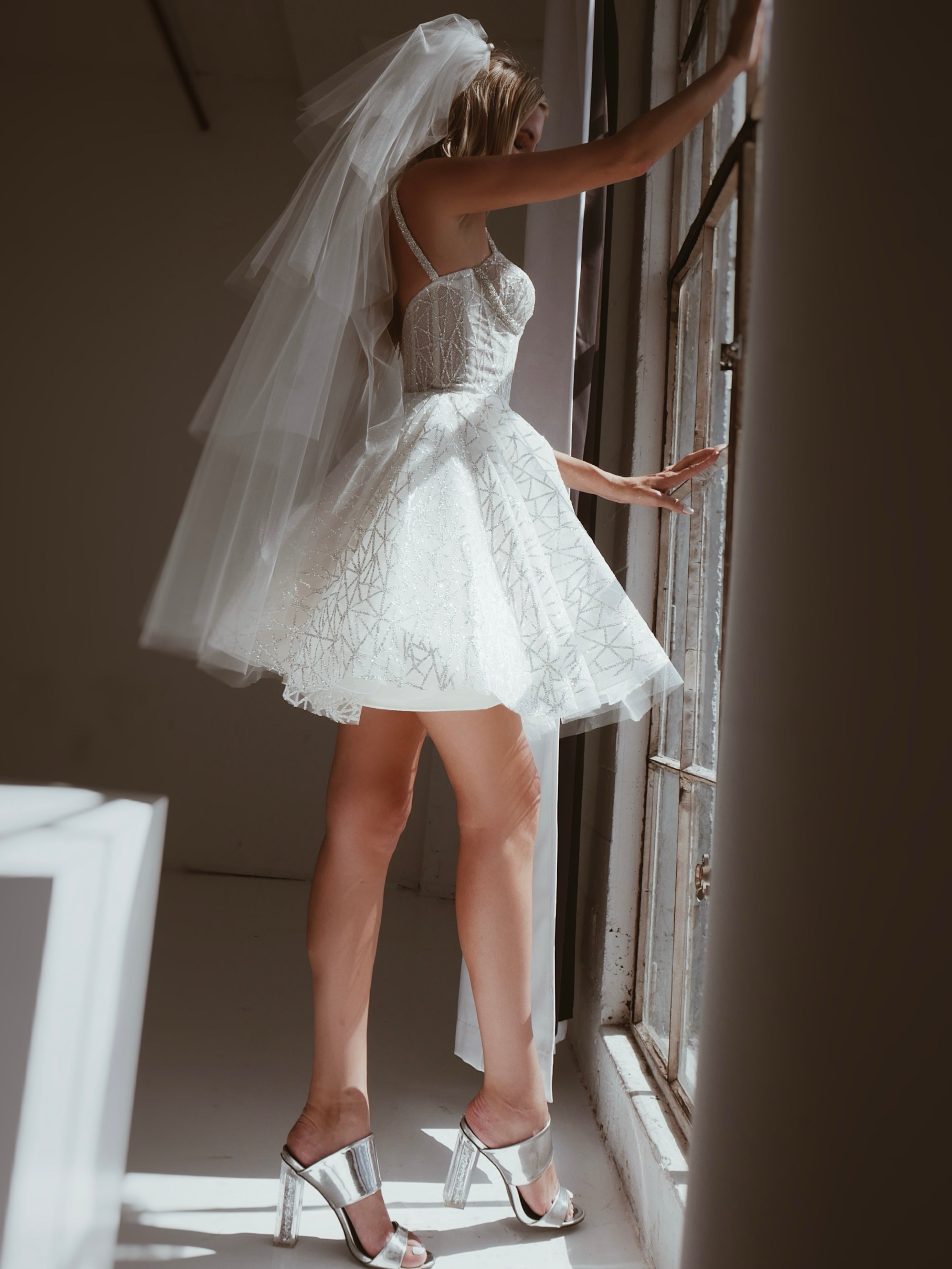 Side view of a model wearing a glamorous tiered tulle wedding veil with crystal comb.