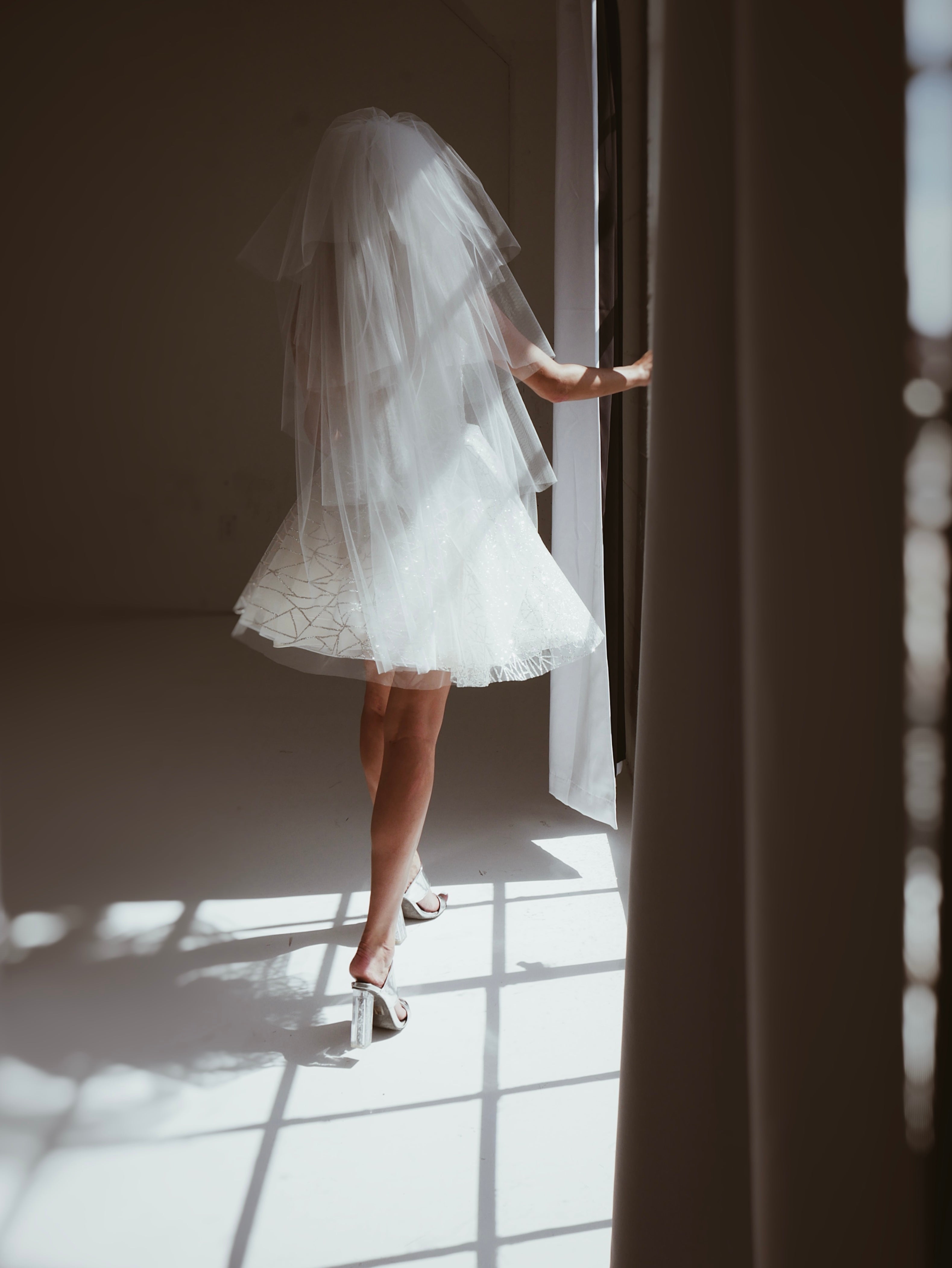 Back view of a model wearing a 1980s style tiered tulle wedding veil with crystal comb.