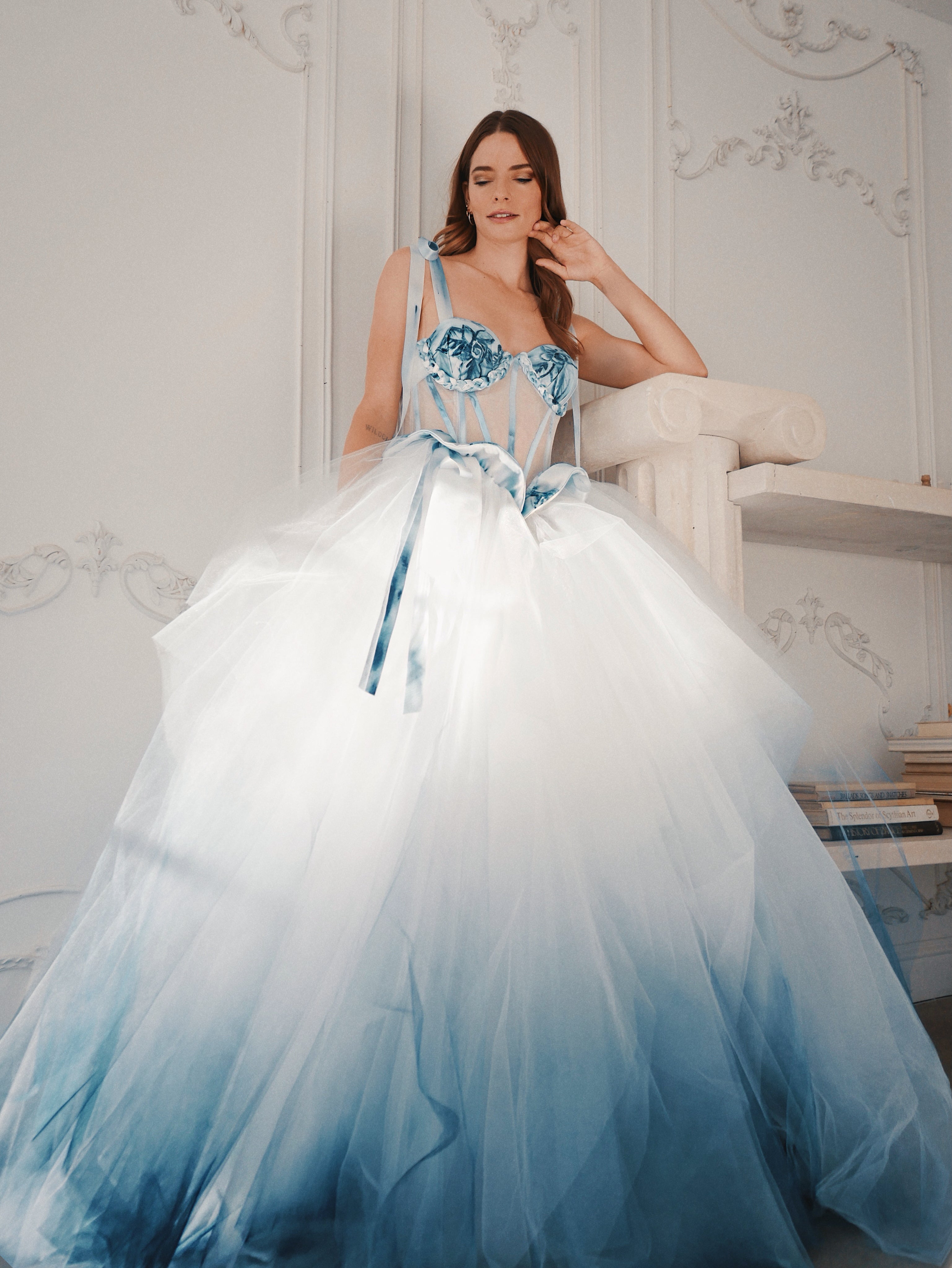 A model poses in a hand painted Prussian blue ombre tulle wedding dress with illusion corset bodice.
