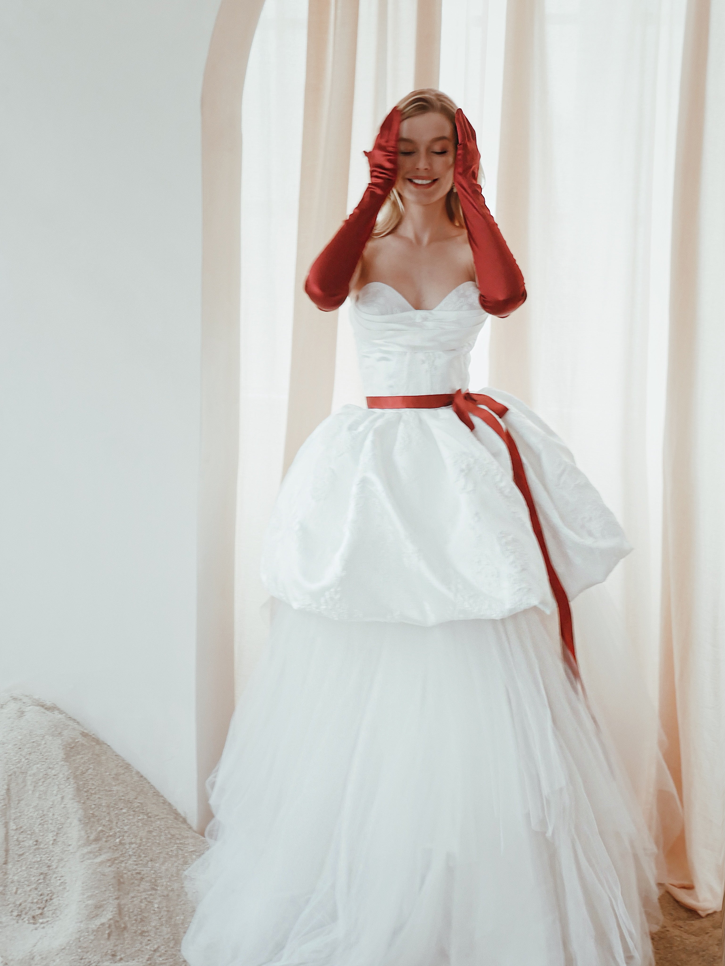 A model poses in a satin bubble hemline wedding dress with detachable tulle underskirt.