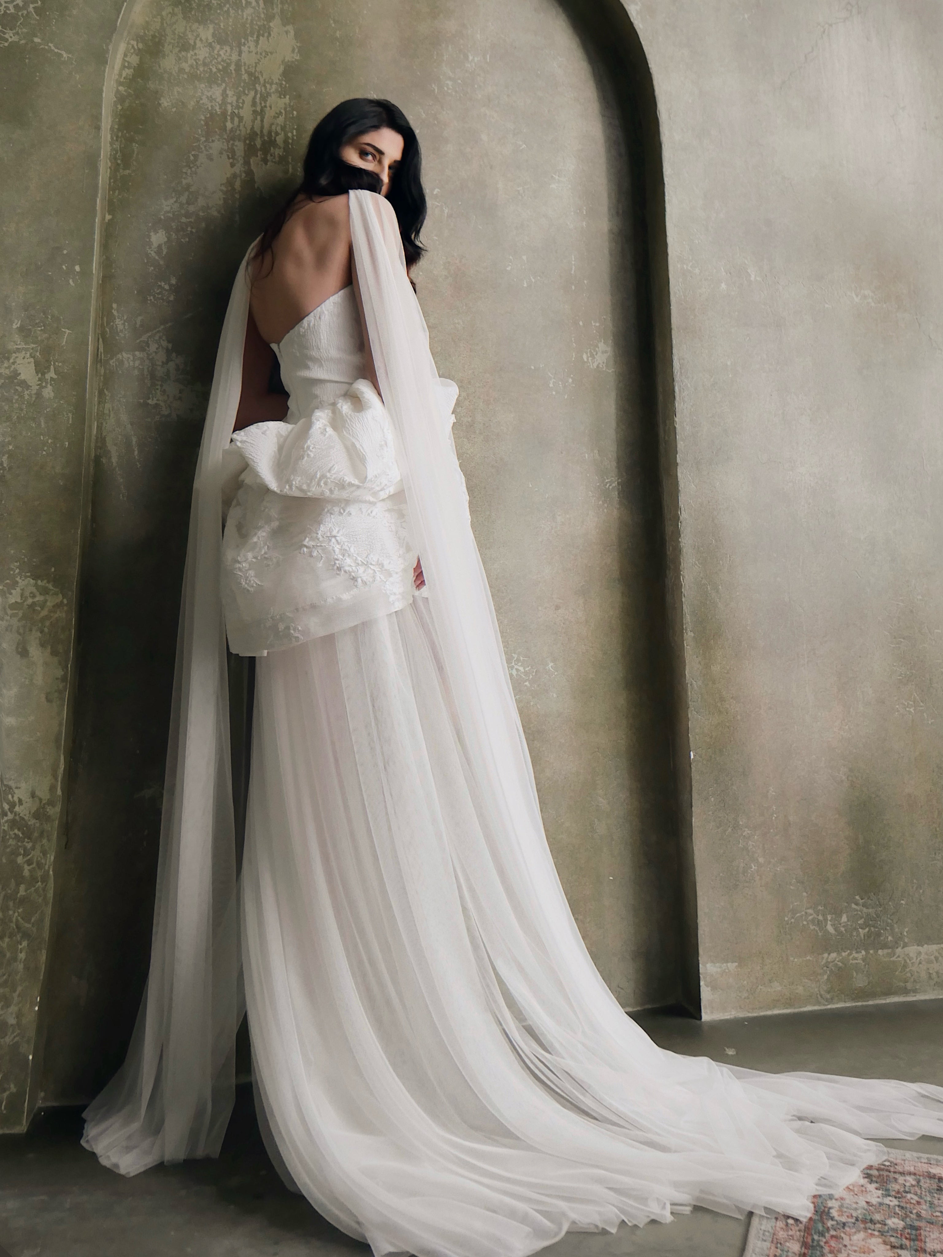 A model poses in a flowing tulle nette bridal scarf for a fashion forward bridal look.