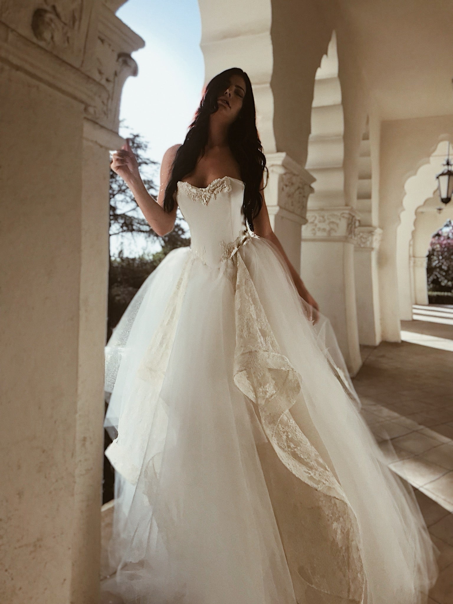 A model poses in a vintage inspired Basque waist satin wedding dress with tulle skirt.