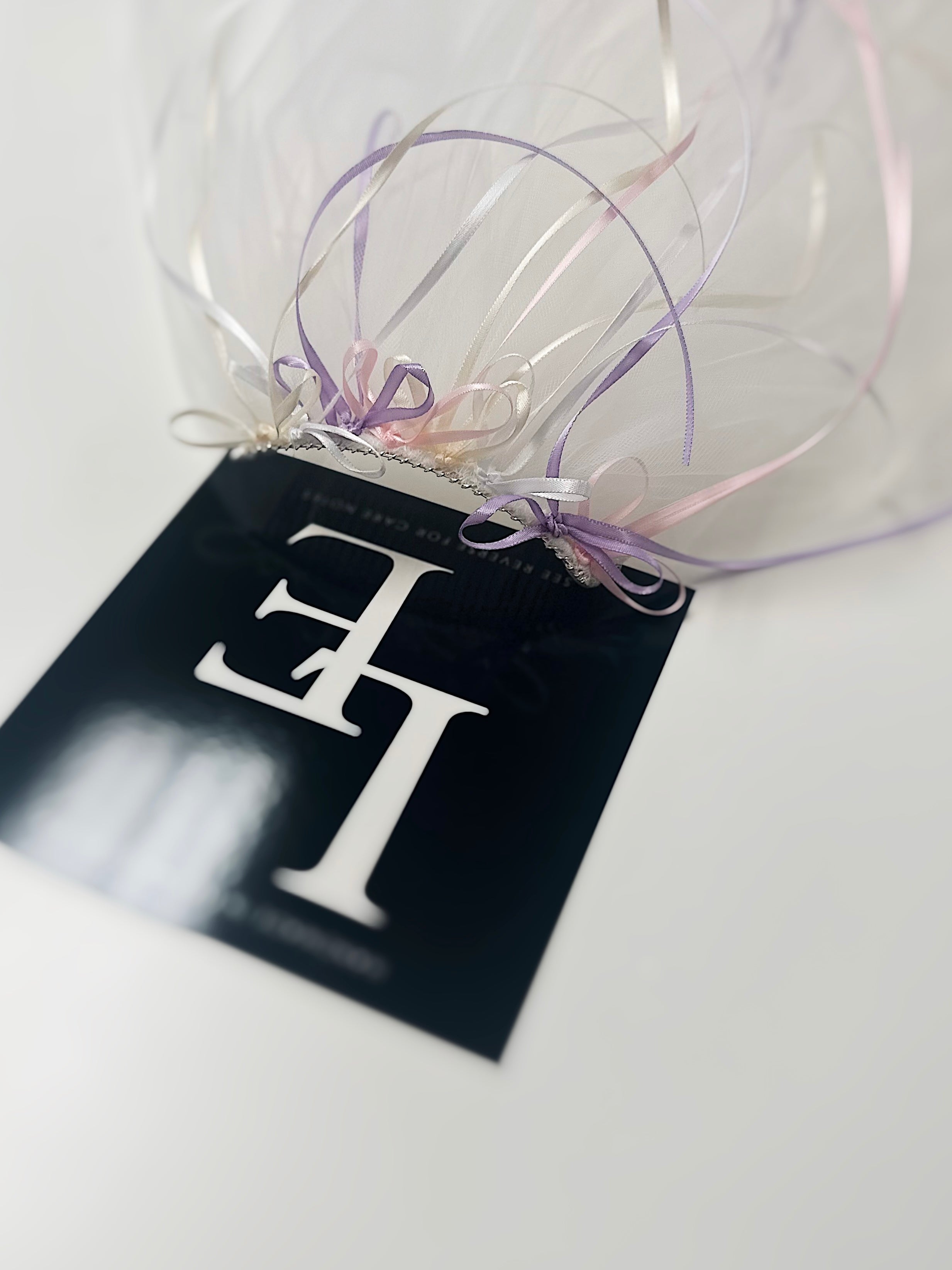 Closeup view of a tulle wedding veil with mini satin bows in shades of pastel blush, lavender, and cream.