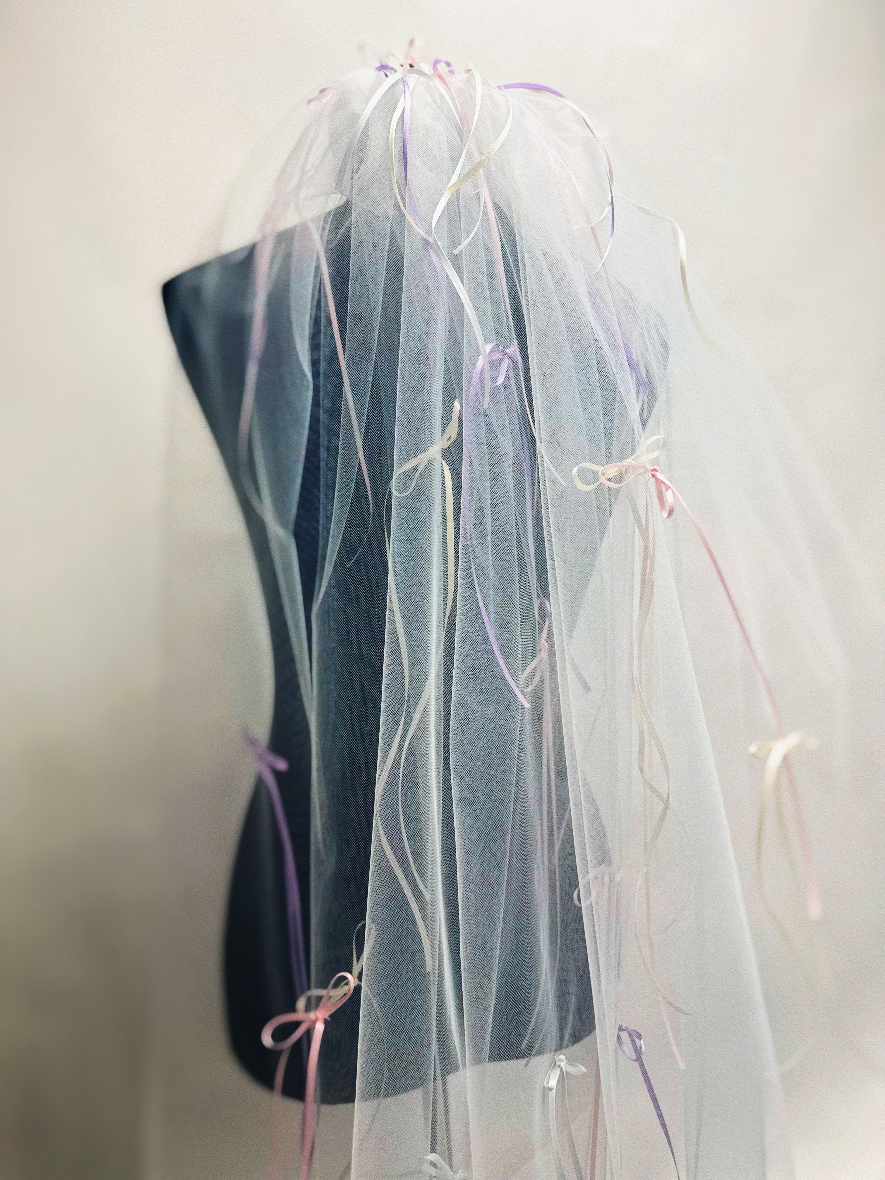 Detail image of a tulle wedding veil with pastel pink and purple bows.