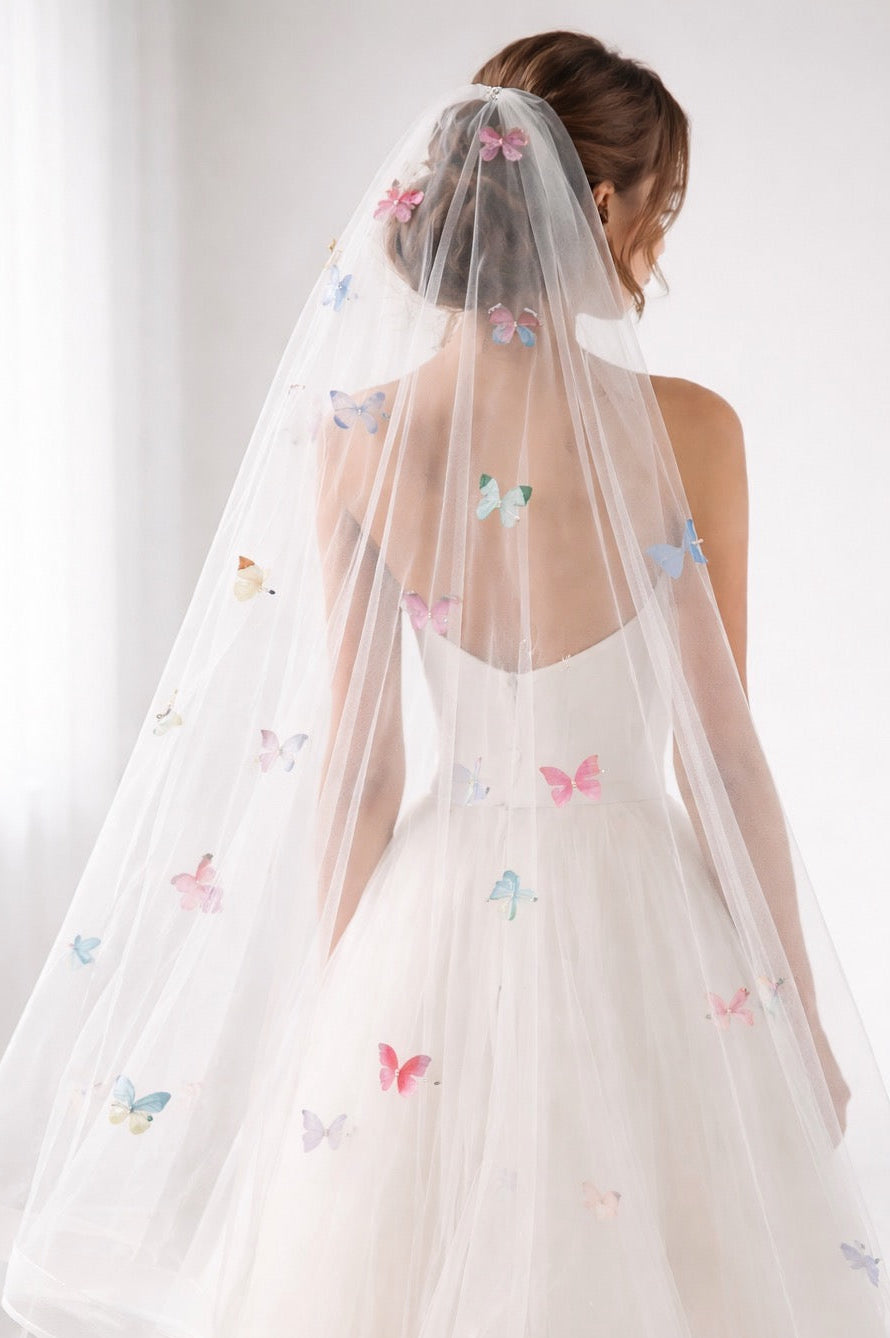 A bride wears a rainbow butterfly wedding veil with horsehair trim and organza butterflies.