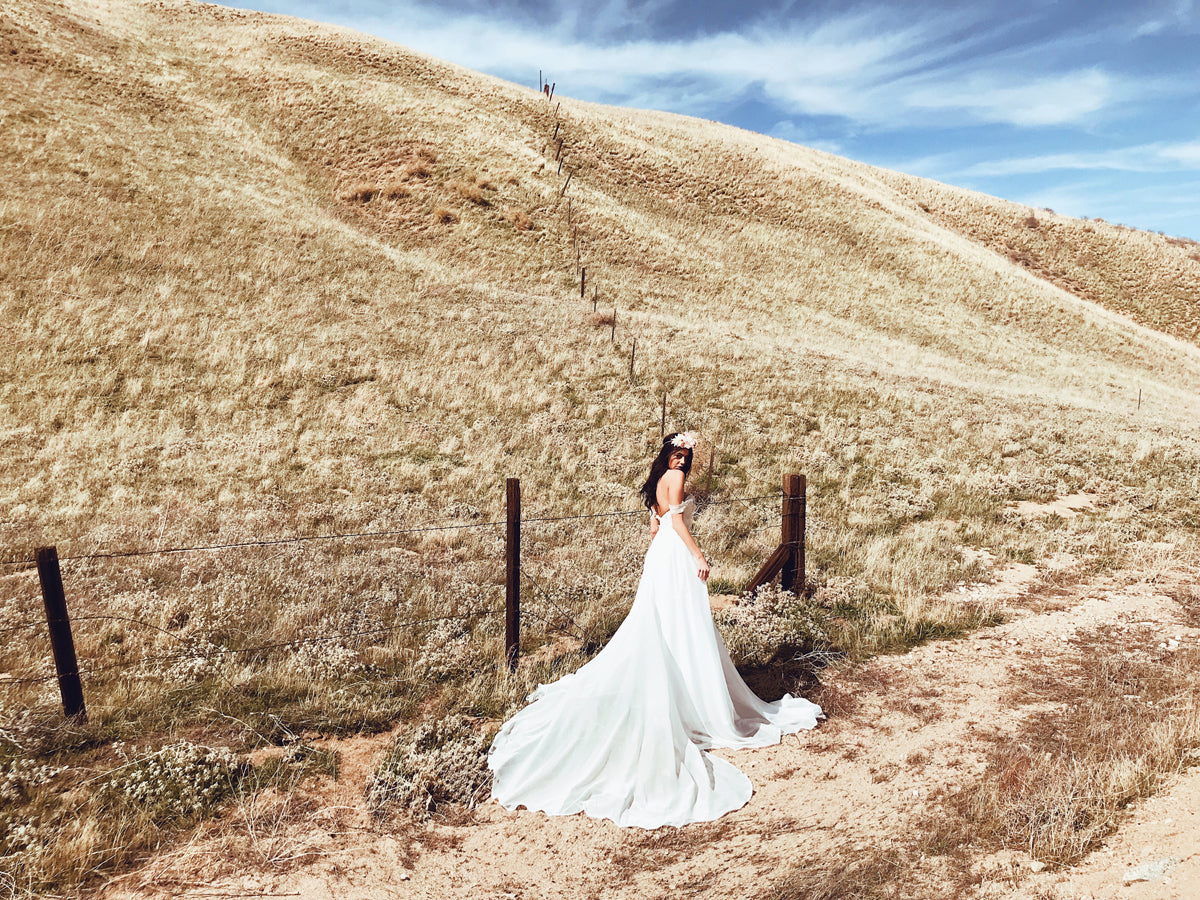 Romantic and bohemian a-line off-the-shoulder wedding dress with floral lace detailing from the affordable 'Pearl by Lauren Elaine' Bridal Collection
