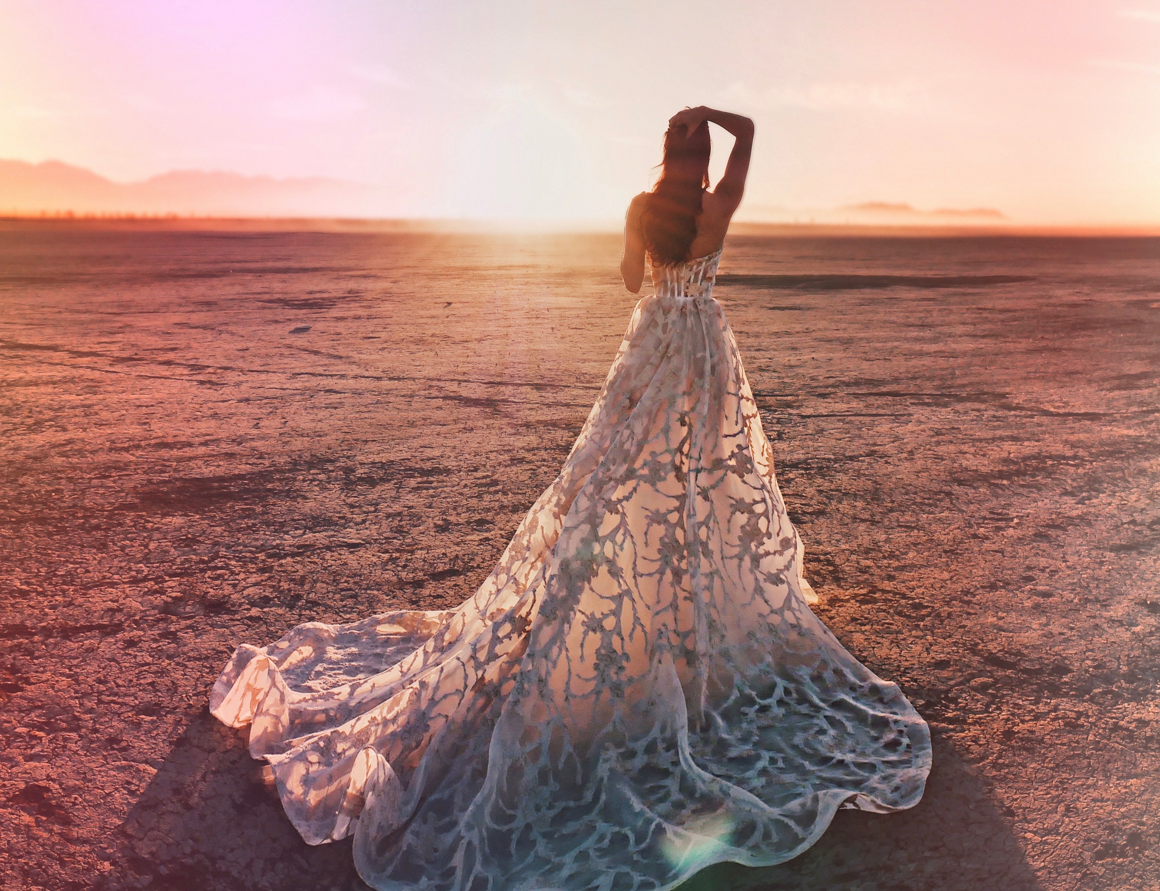 Back of bustier corset wedding dress with hand on head in desert