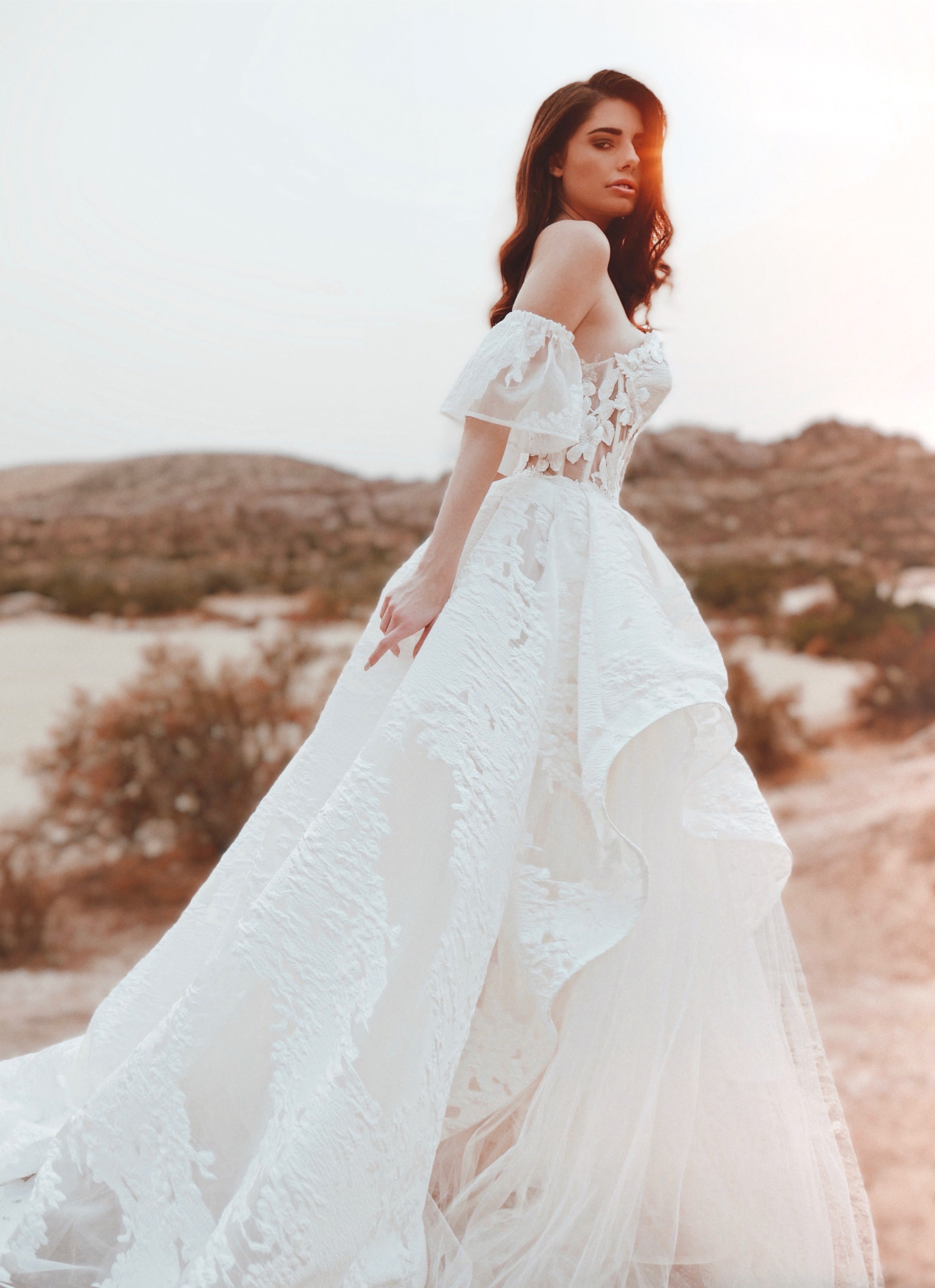 Side video of a model wearing a brocade floral organza corset wedding gown with detachable sleeves.