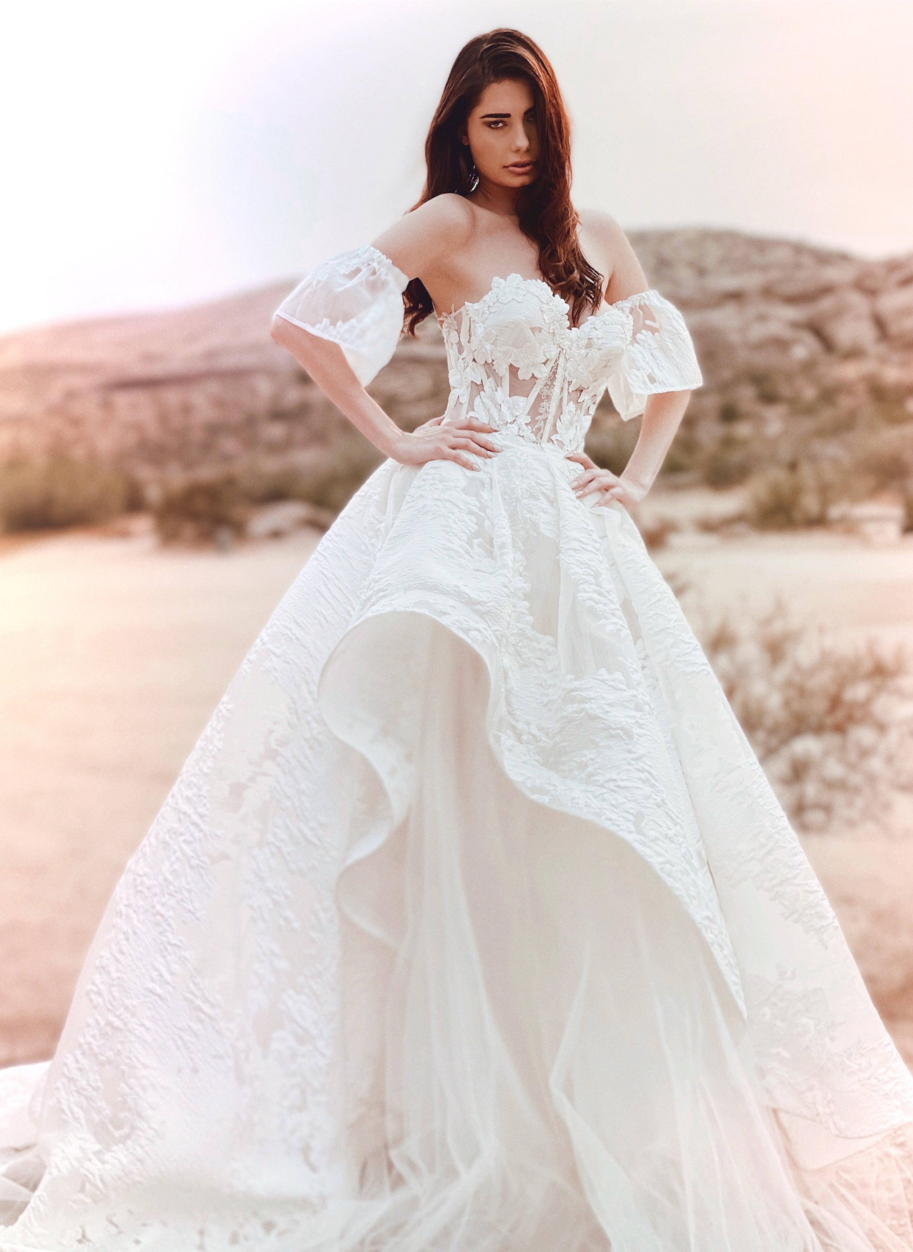 A model poses from the front in a brocade floral organza corset wedding gown by Lauren Elaine.