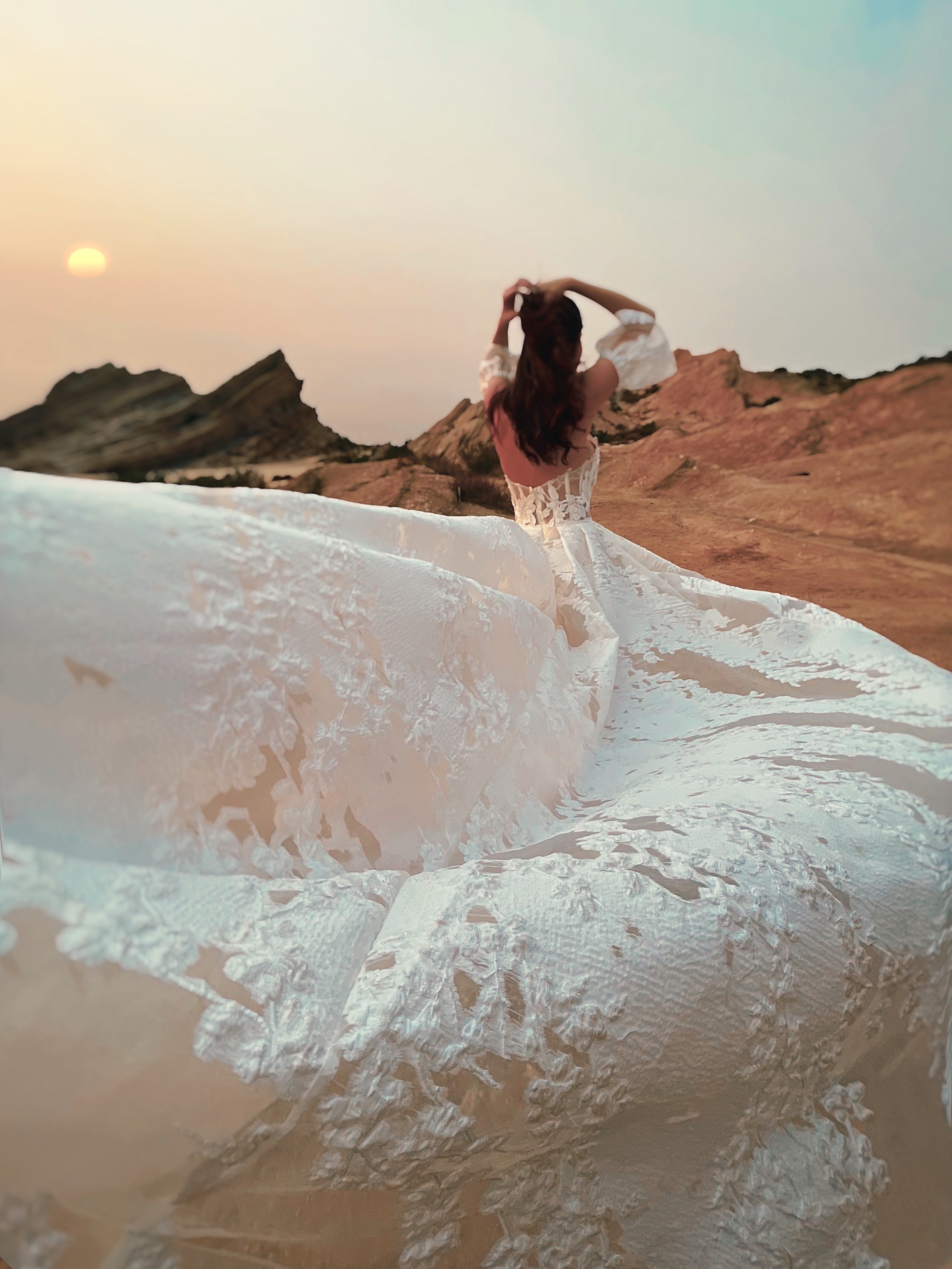A cathedral organza wedding dress train blows in the wind at Vasquez Rocks, ca.