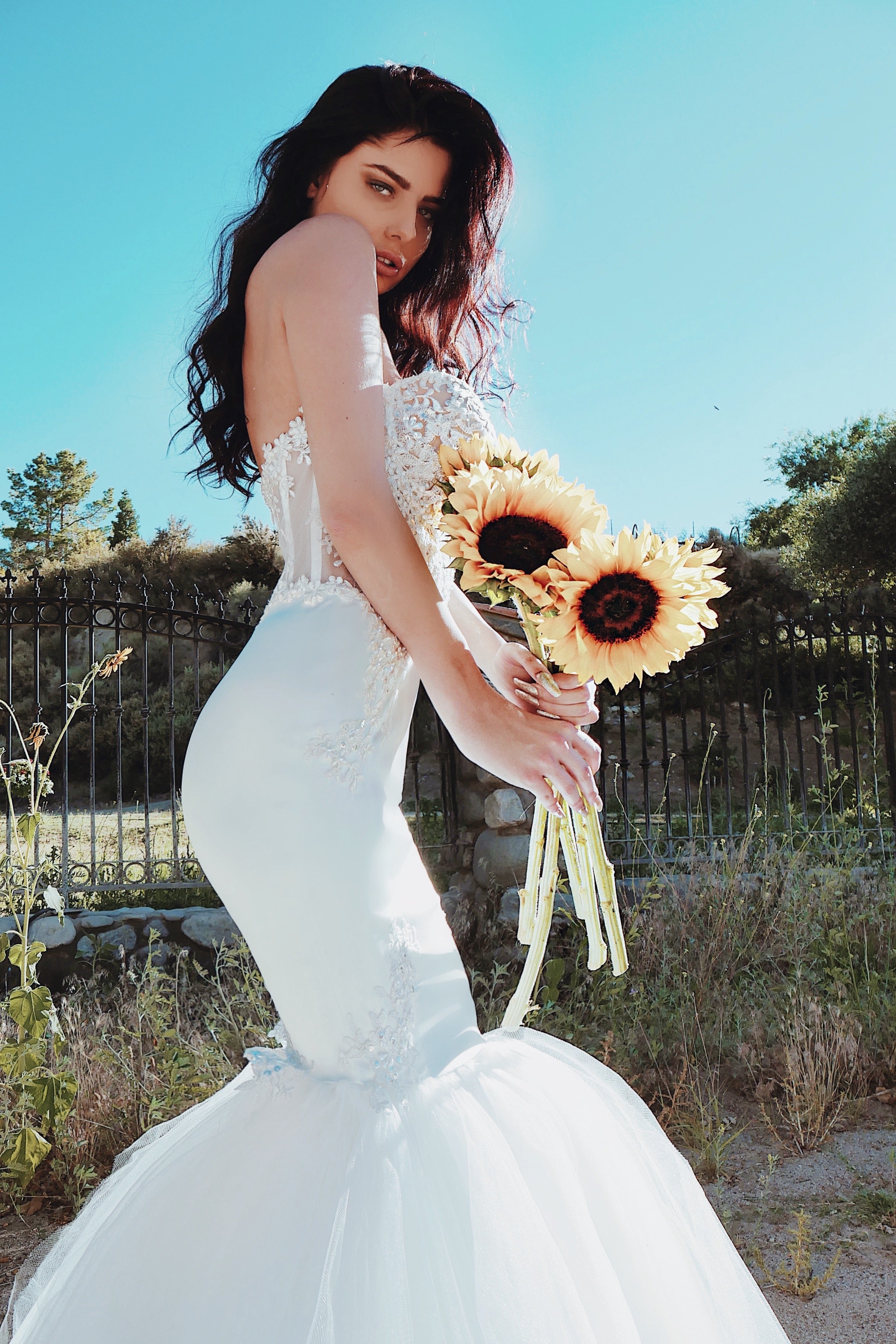 Lace applique wedding dress with satin hips and mermaid skirt holding sunflowers