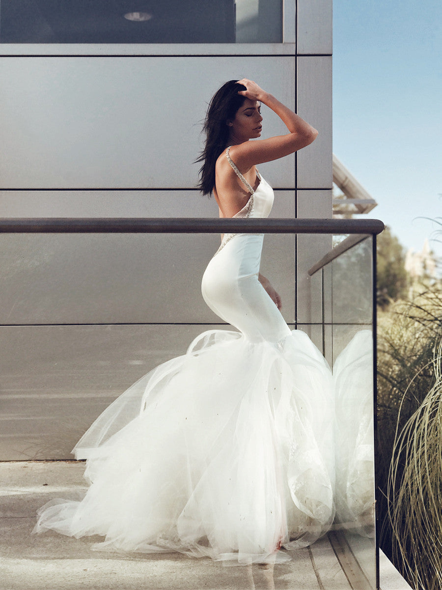 Satin mermaid wedding gown on model with hand on head behind glass