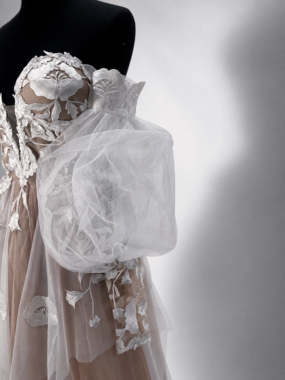 Arrowyn illusion corset wedding dress with hand-applied botanical appliqué and detachable tulle gigot sleeve.