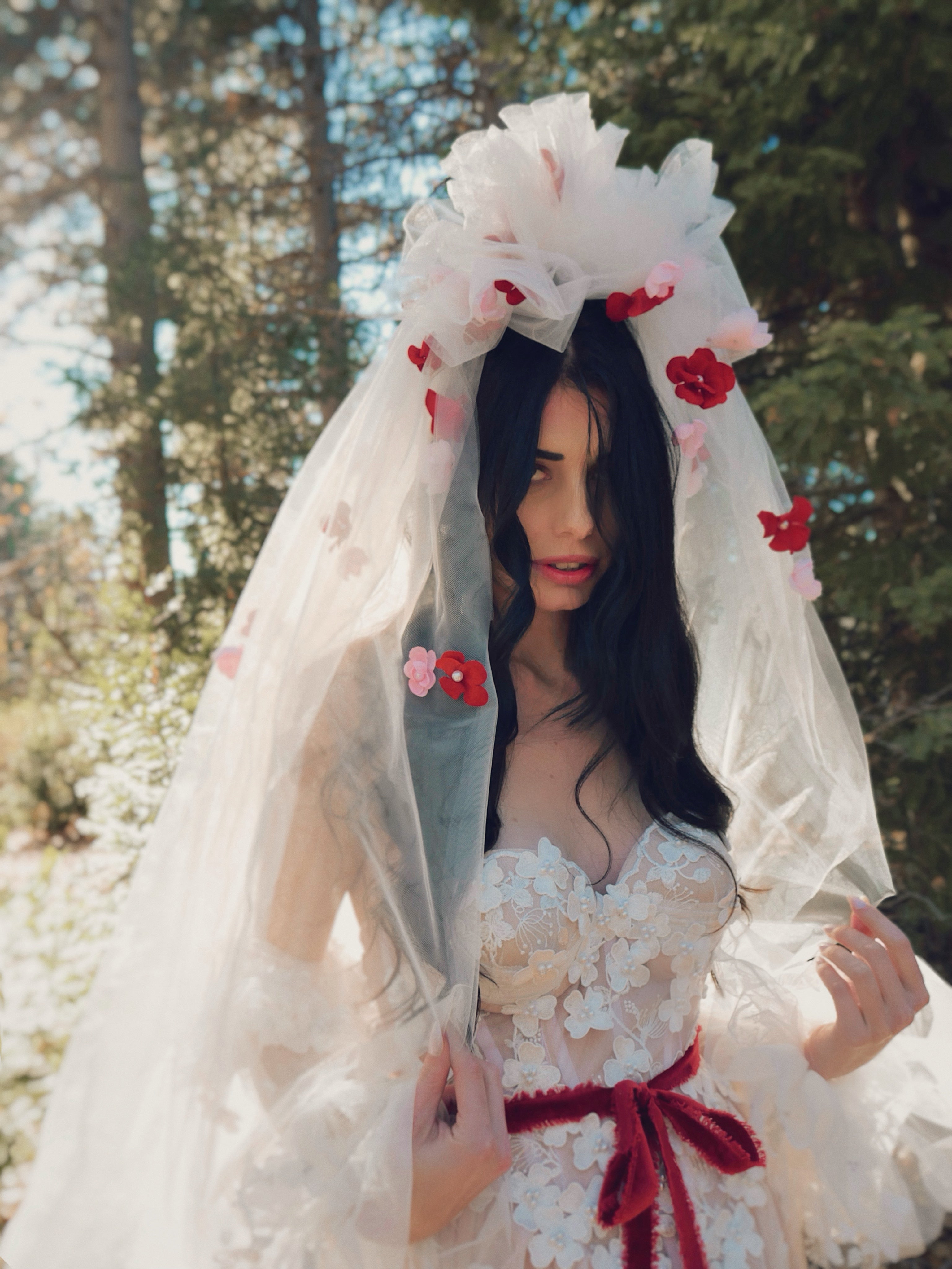 Bride wearing the CHÉRIE dramatic 1980s-style tulle veil with red and blush 3D flowers by Lauren Elaine.