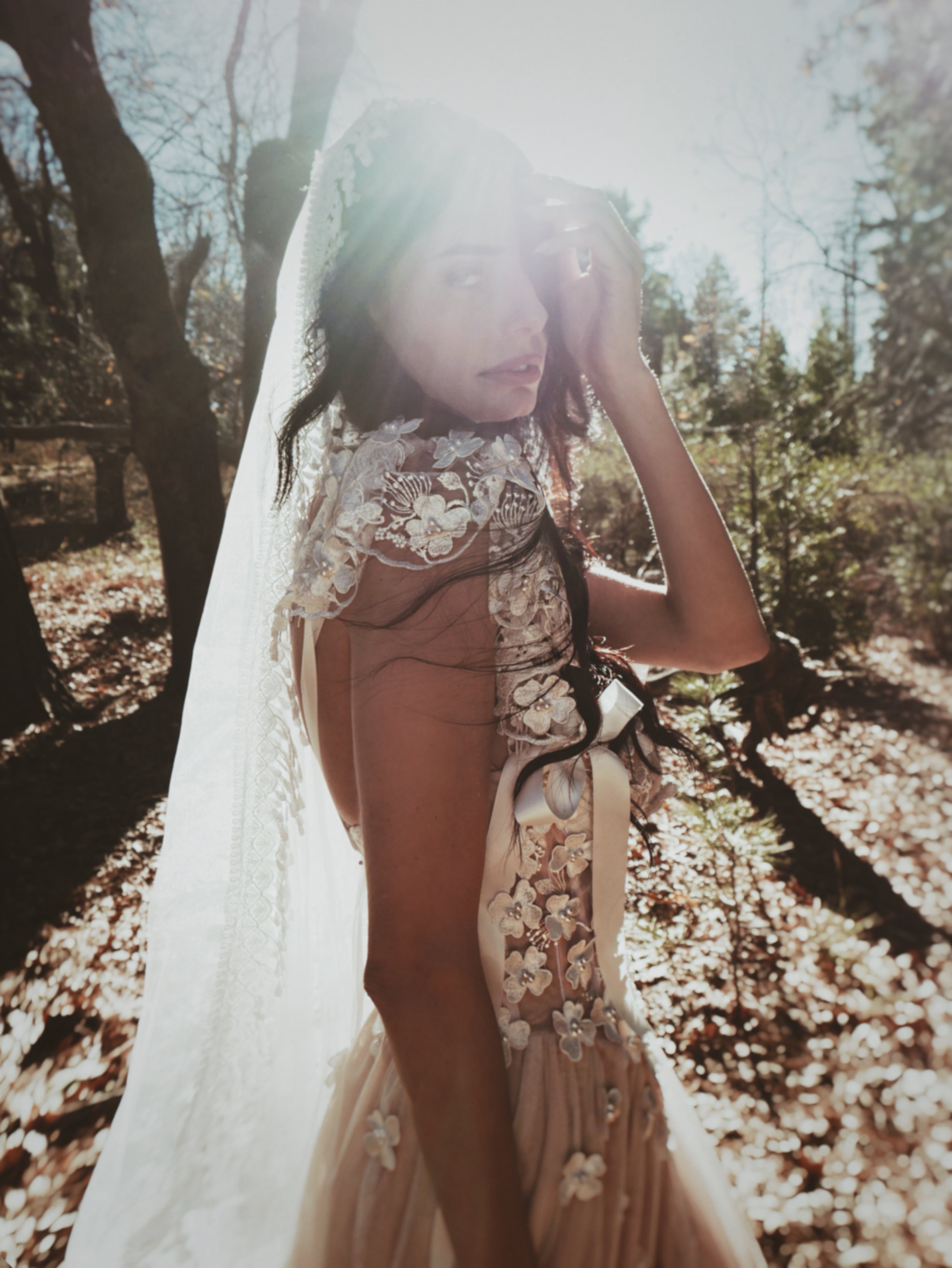 Bohemian style mantilla wedding veil with crochet lace fringe, worn with an ethereal floral wedding dress in natural outdoor light
