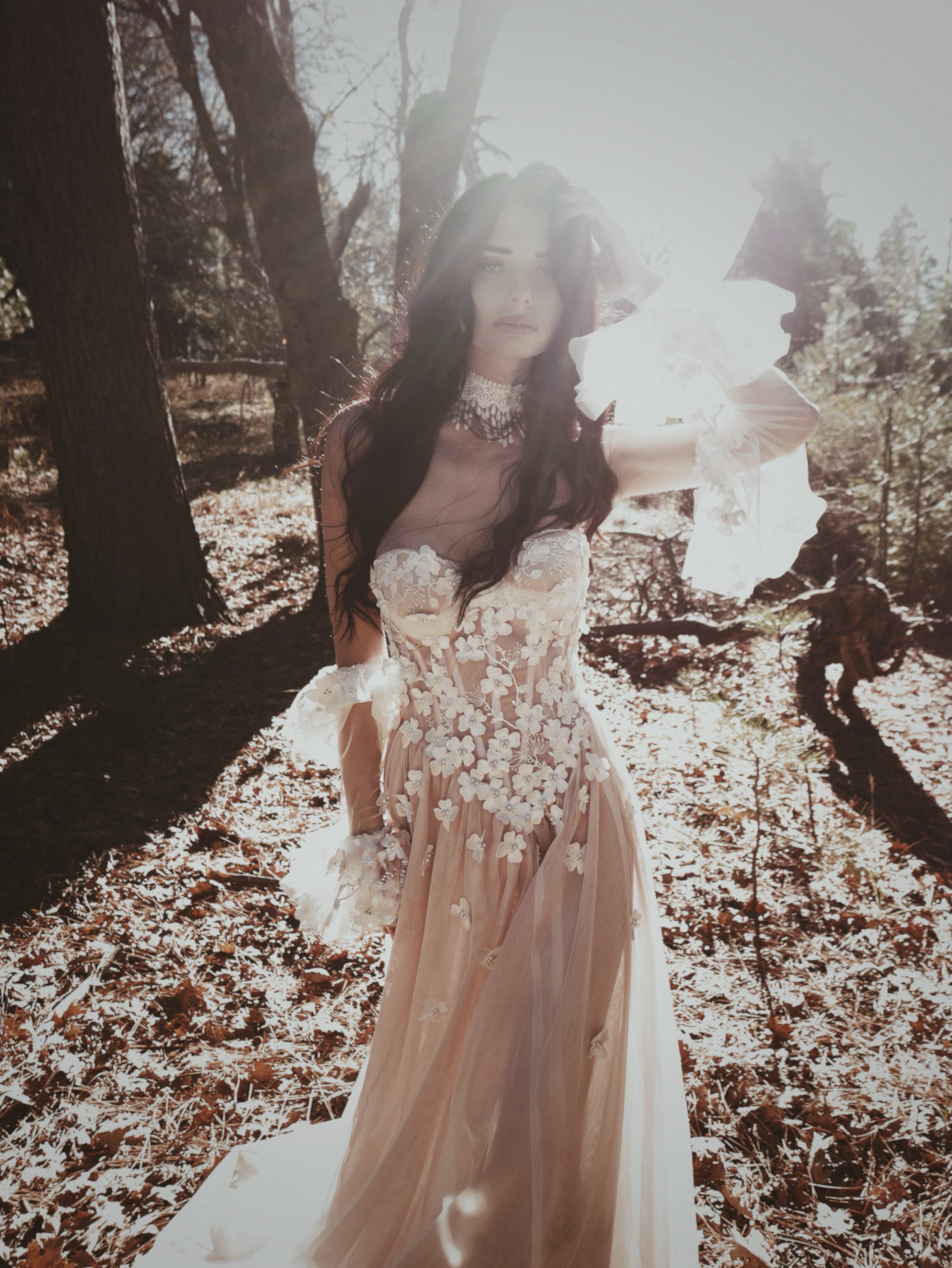 Valen ethereal bridal gown featuring detachable floral tulle sleeves, sheer corset bodice, and soft romantic A-line silhouette on a bride in a forest