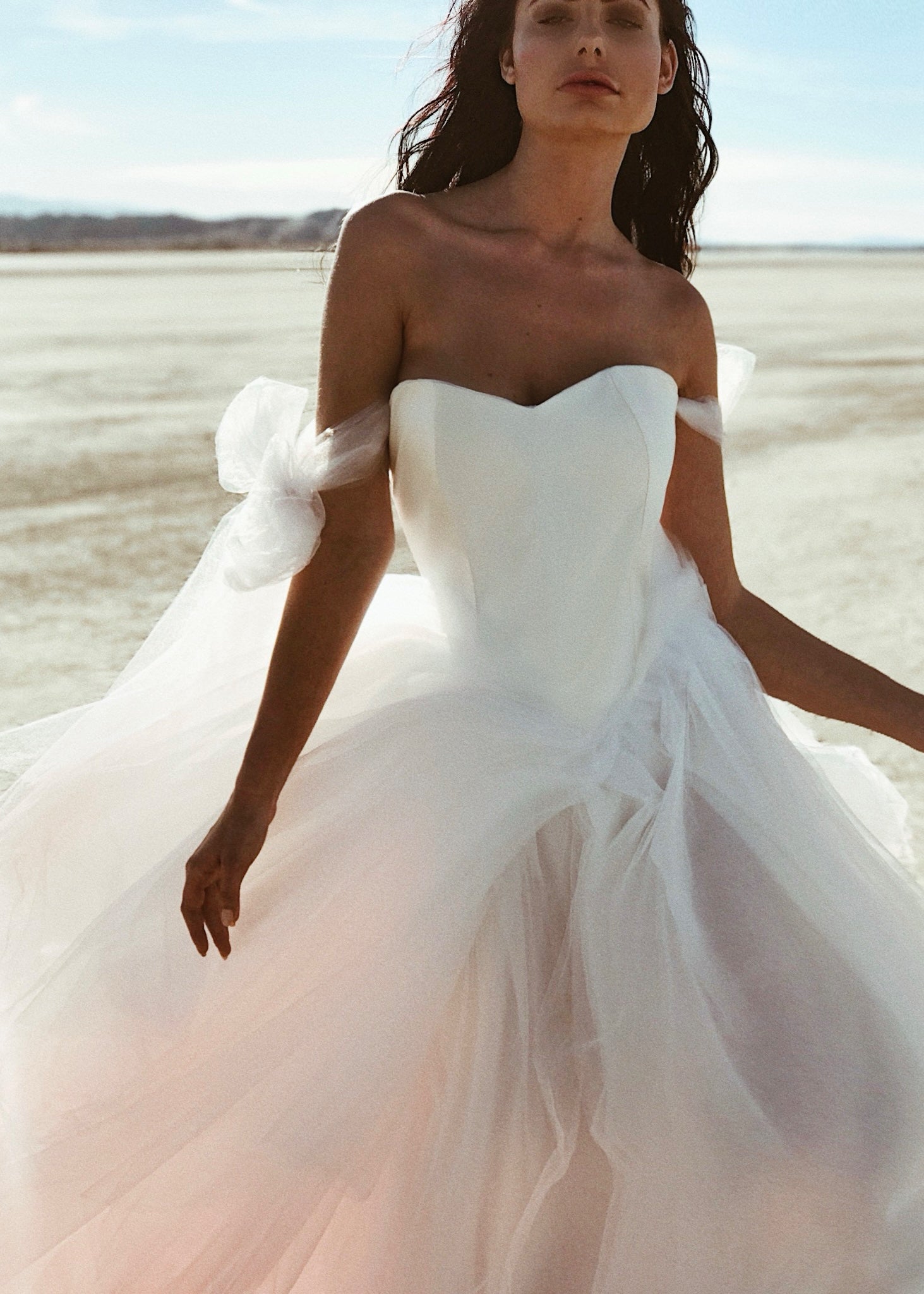 Close up view of a model wearing the Lauren Elaine Basque Waist "Aria" satin blush Wedding Dress