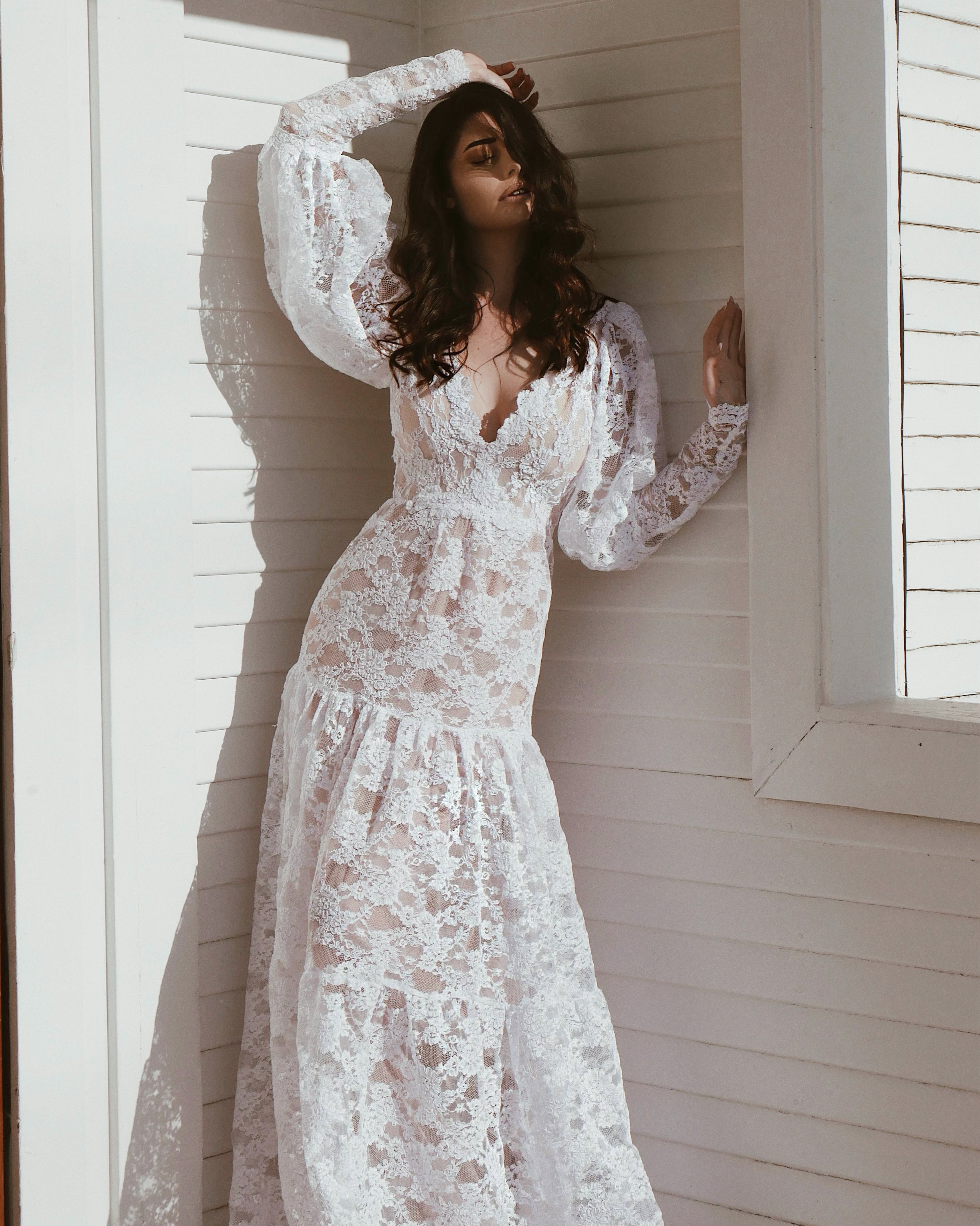 A model poses in gigot style lace sleeves for a bridal fashion editorial, front.