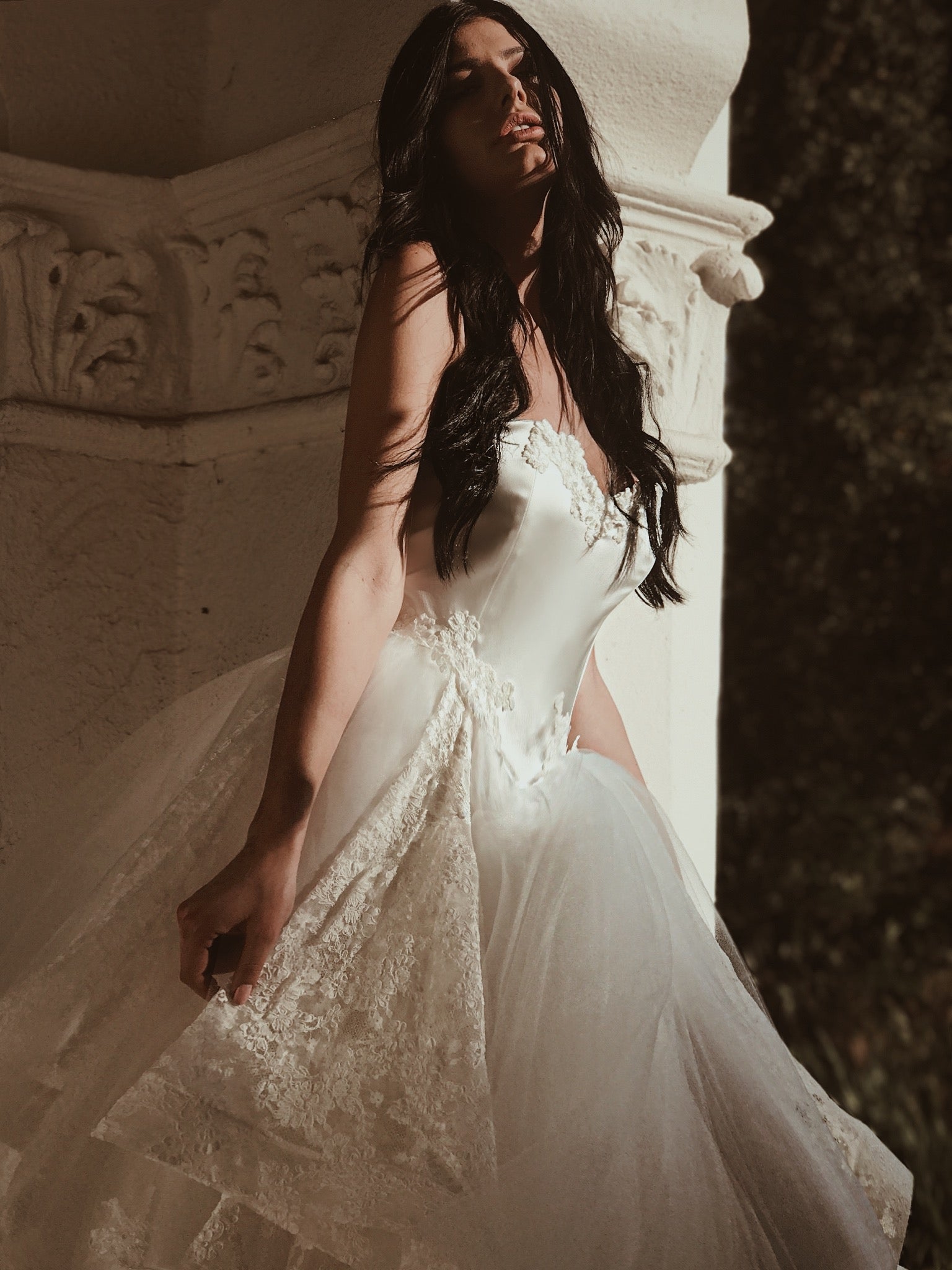 A model wears a tulle ball gown wedding dress with dramatic detachable cathedral train - front view.