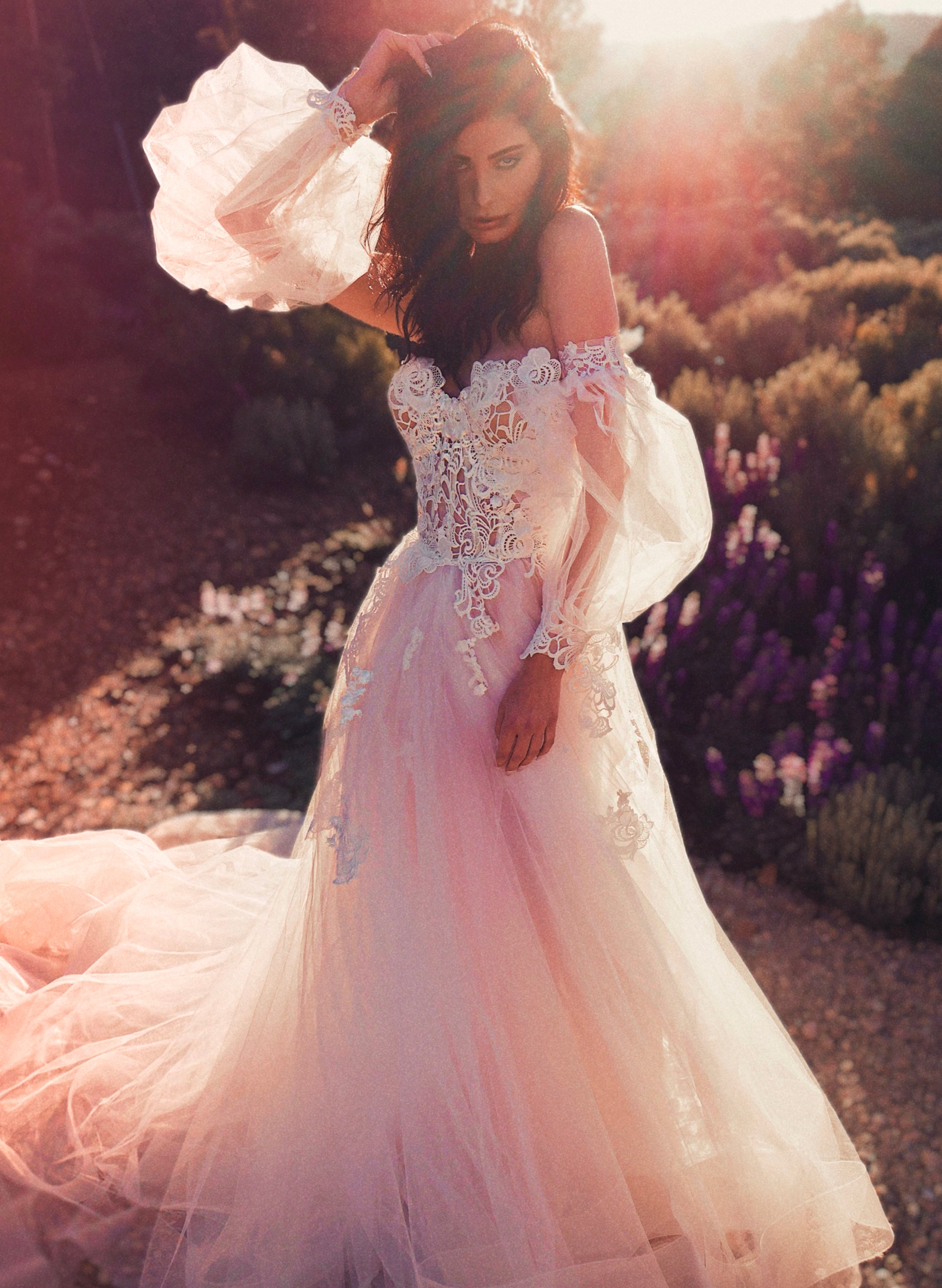 A model wears the Lauren Elaine Pastora guipure lace corset wedding gown with bishop sleeves