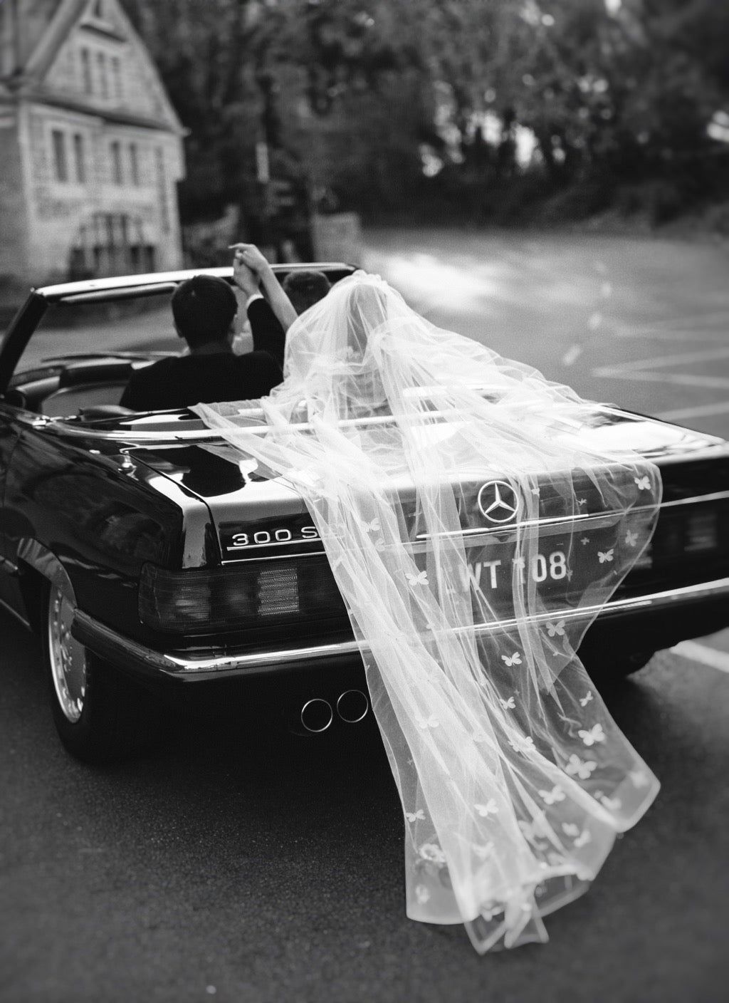 A couple's 'just married' wedding send off with dramatic butterfly veil in a vintage convertible