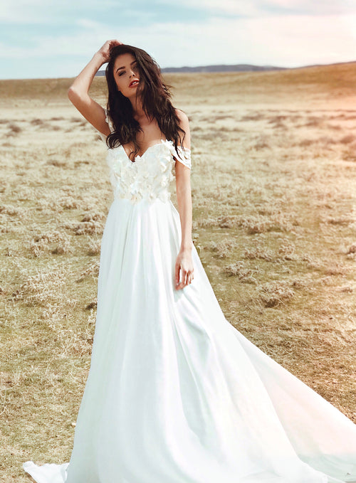 Off-the-shoulder sweetheart bodice a-line wedding dress with lace floral appliques and flowing chiffon skirt. Chrysalin gown from the Pearl by Lauren Elaine Bridal collection.
