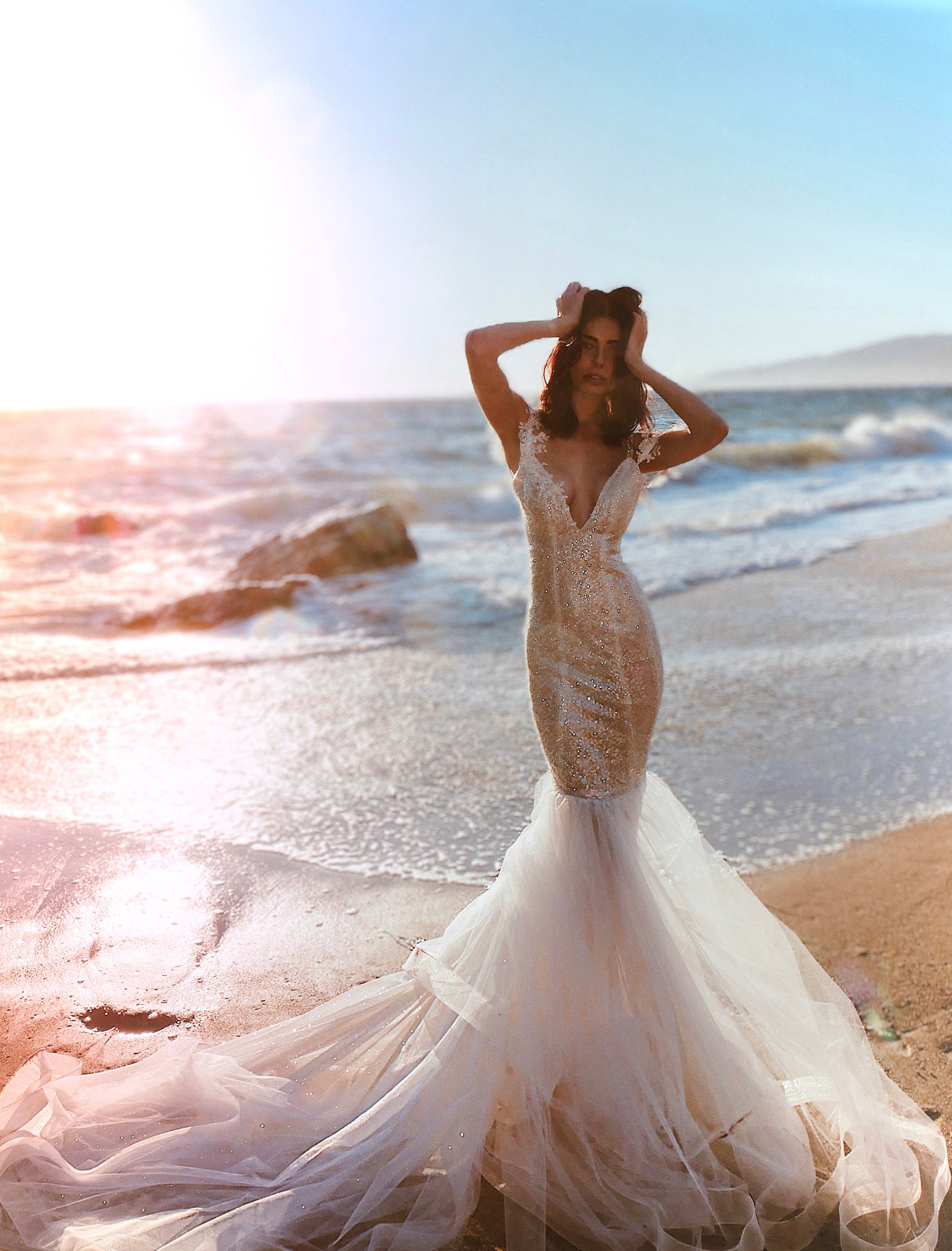 A model wears a Lauren Elaine Lustra wedding dress on a beach in Malibu, Ca.