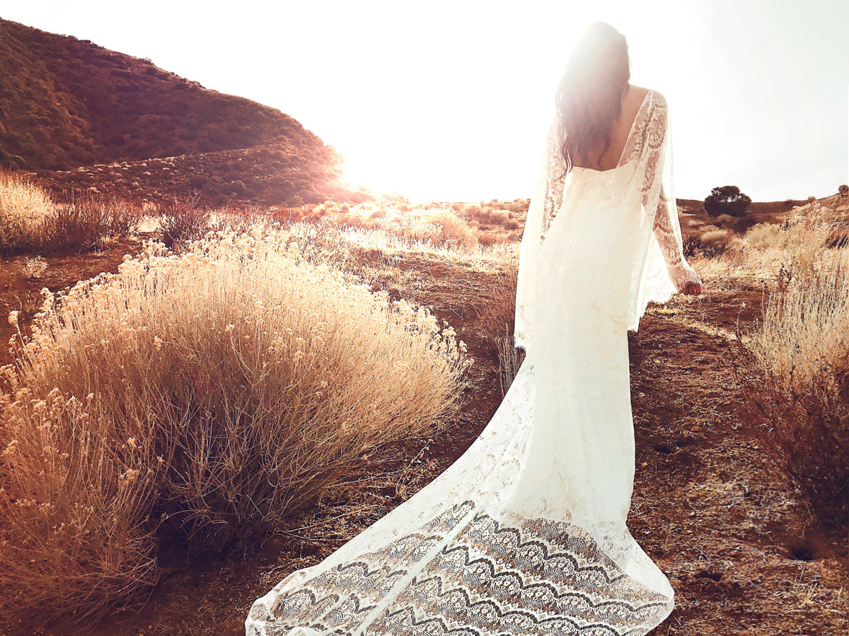 Ethereal and bohemian lace sheath wedding dress with cape sleeves from Lauren Elaine Bridal.
