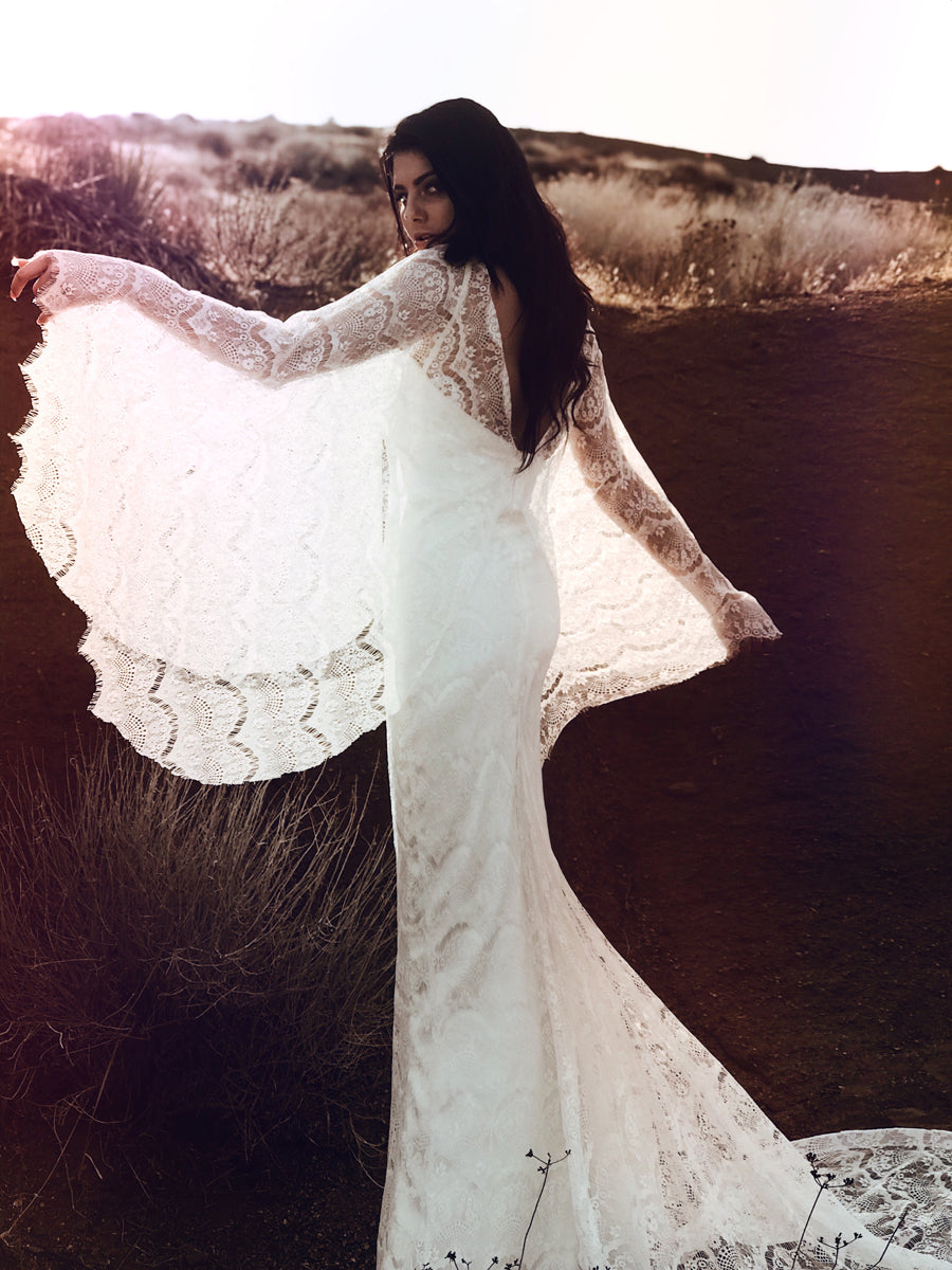 Bohemian beach and destination wedding dress with festival inspired cape sleeves.